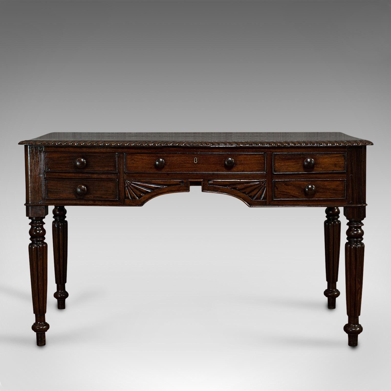 This is an antique writing desk. An English, solid rosewood five-drawer study or side table, dating to the Regency period, circa 1820.

Beautiful writing desk with wonderful carved detail
Displays a desirable aged patina
Select rosewood shows