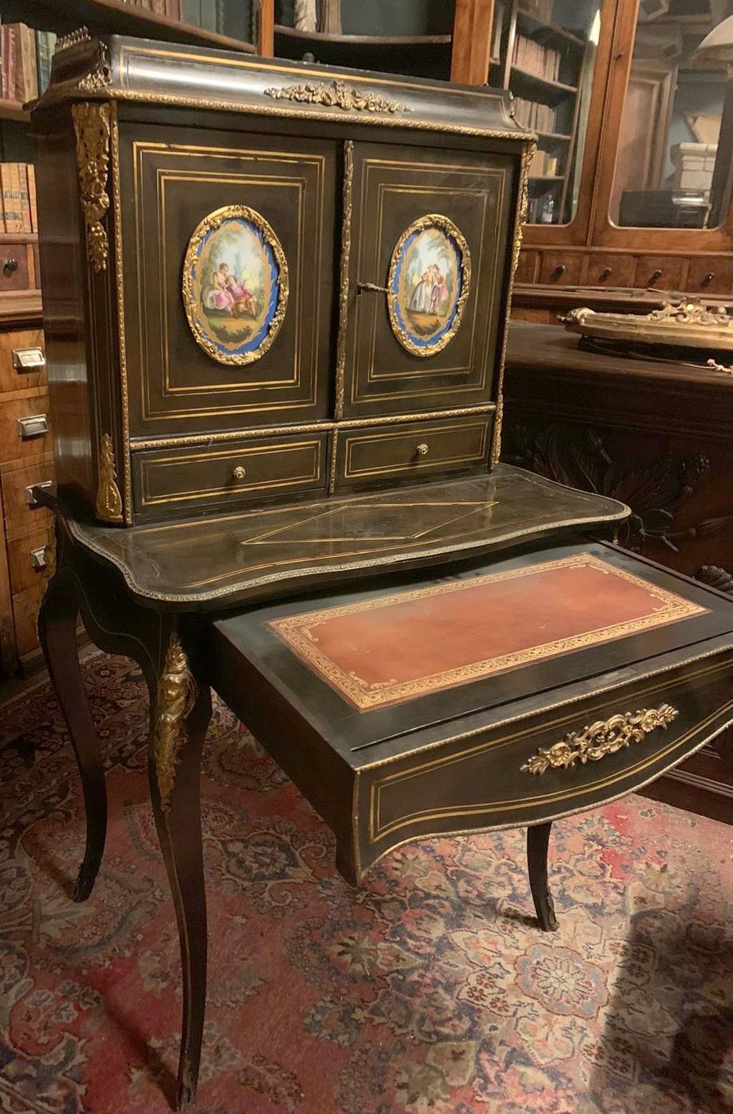 Antique writing desk with raised doors, enriched with bronze and brass ornaments and ovens with ceramics from Sèvres (France) on doors, has a very beautiful and complete removable top, built and decorated in the second half of the 19th century, in