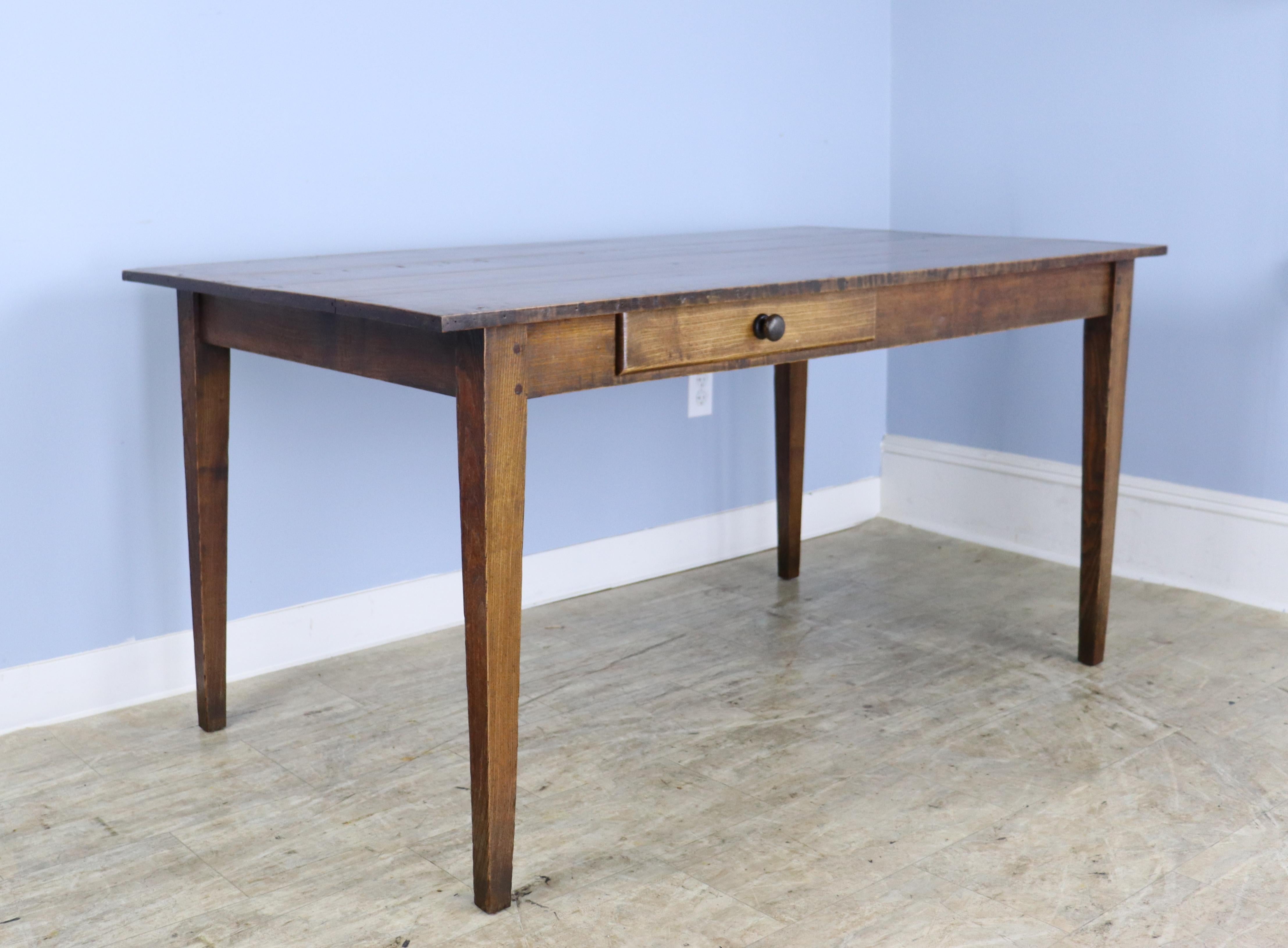 A simple, elegant and beautifully grained writing table or desk with a fruitwood top and an oak base. This piece is in very good antique condition with few flaws and a handsome presence. 24.5 inch apron height is just right for knees.  There are 50
