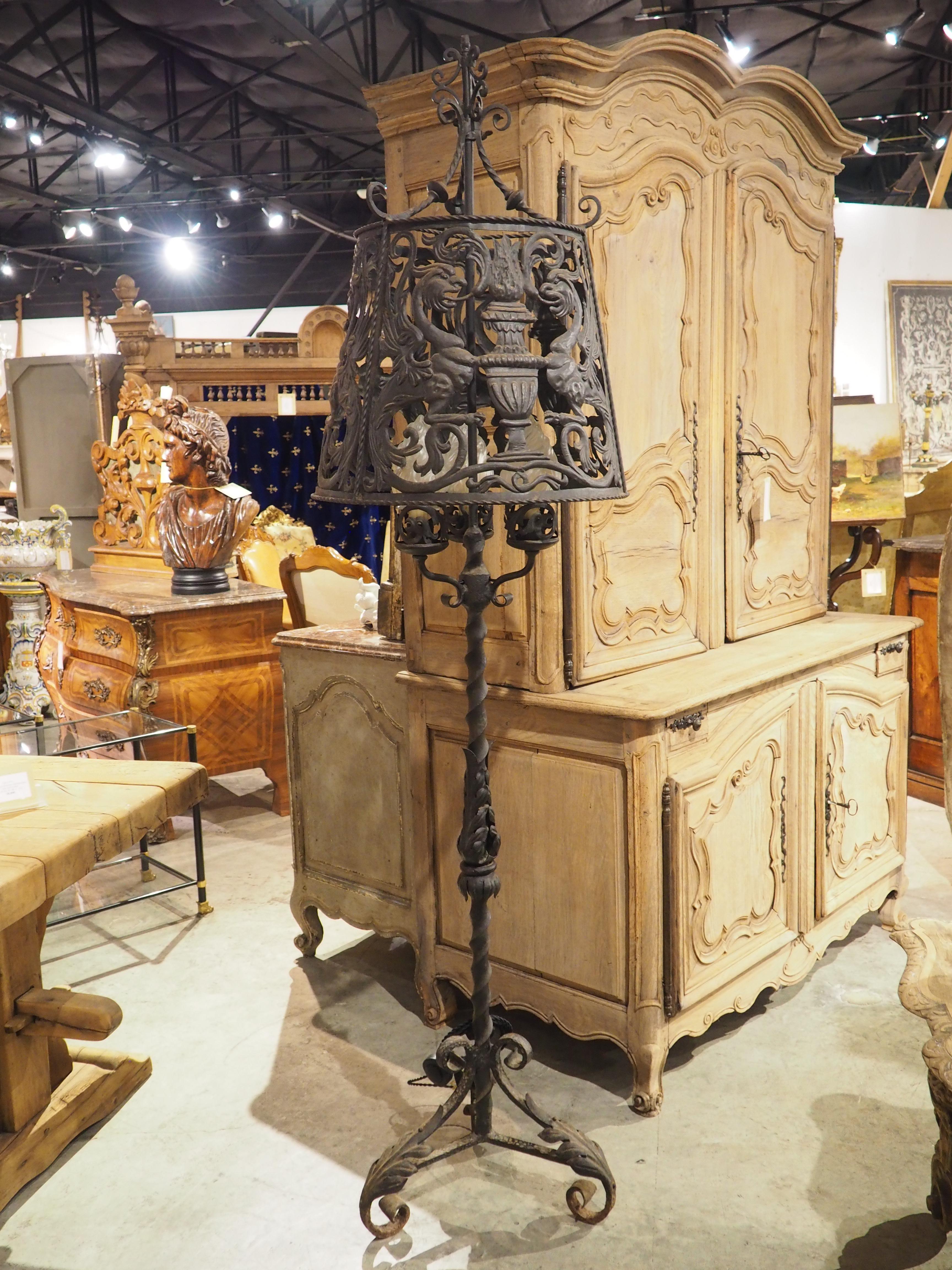 A wonderfully detailed wrought iron lamp from Catalonia, Spain (circa 1900), this three-light floor lamp features foliate motifs and three sets of mythical creatures with flaming pots. Standing almost seven feet tall (83 ½ inches), the lamp also has