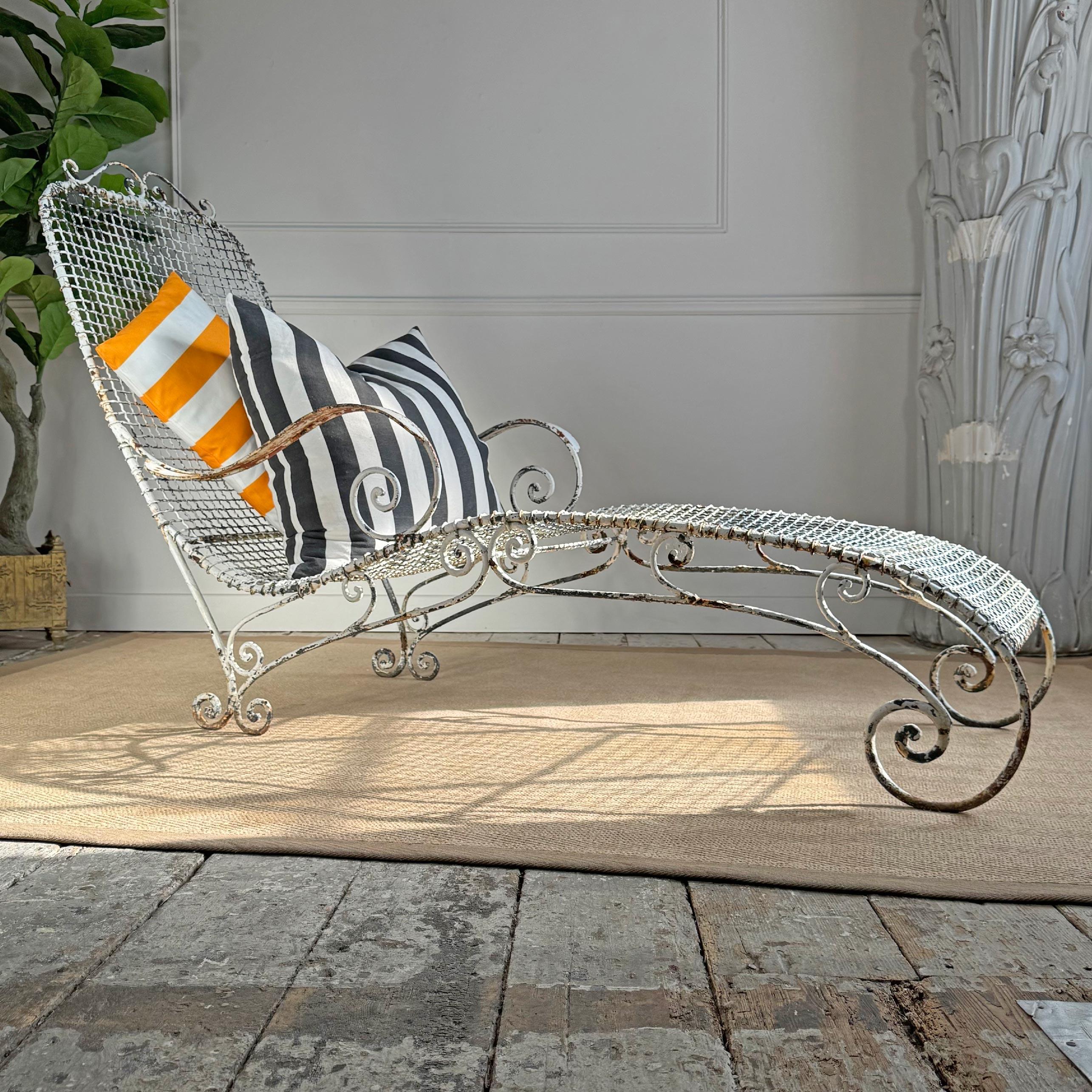 A jaw-droppingly beautiful antique wirework and wrought iron pool side or garden lounger, resplendent with scroll arms, and legs, all the iron work and wire work is in exceptional condition, with time worn historic paint, the swooping form of this