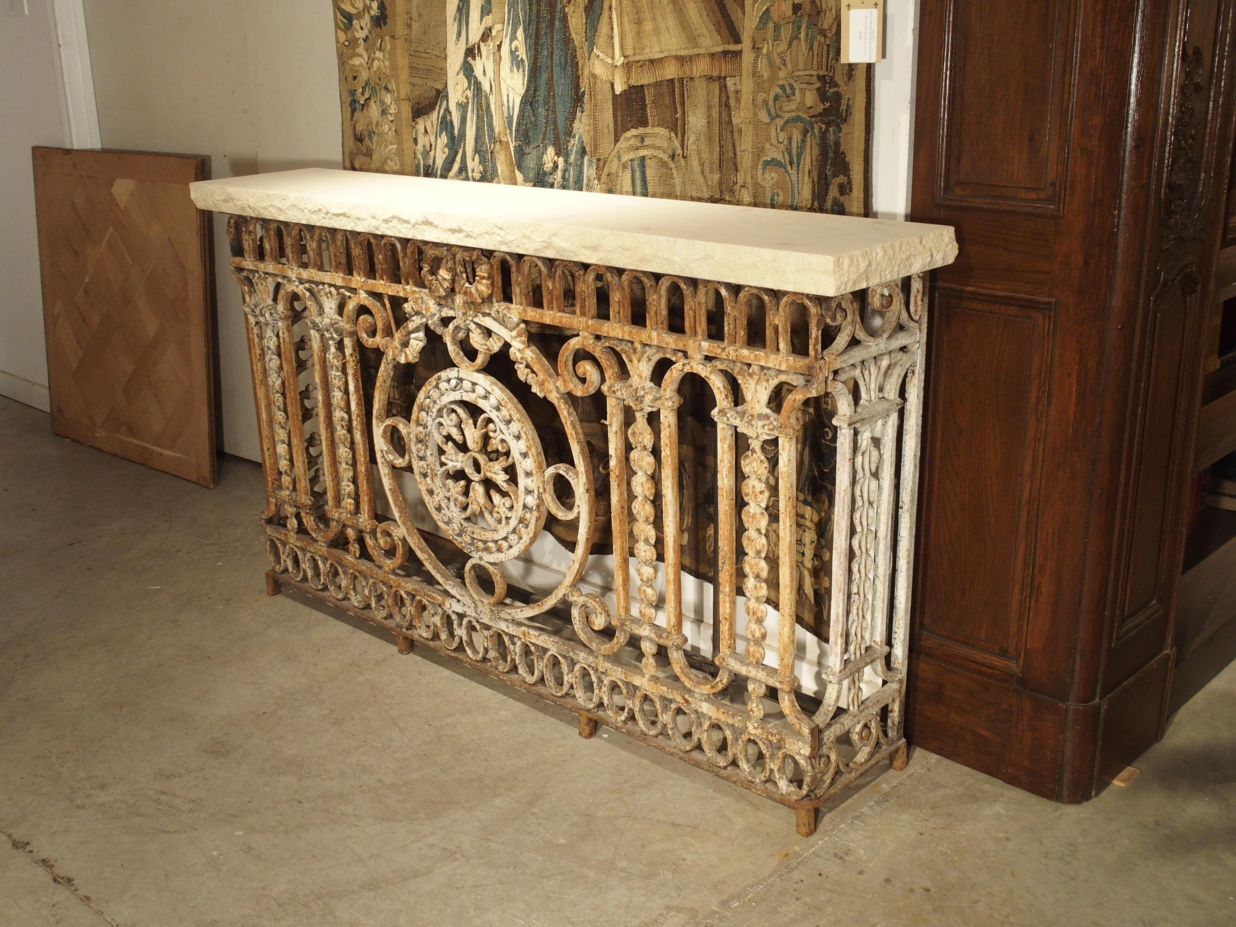 Originally functioning as a balcony barrier, this antique painted wrought iron railing has been repurposed into a console table with a cream-colored limestone top. It was salvaged from a French style building in Argentina, which would have been