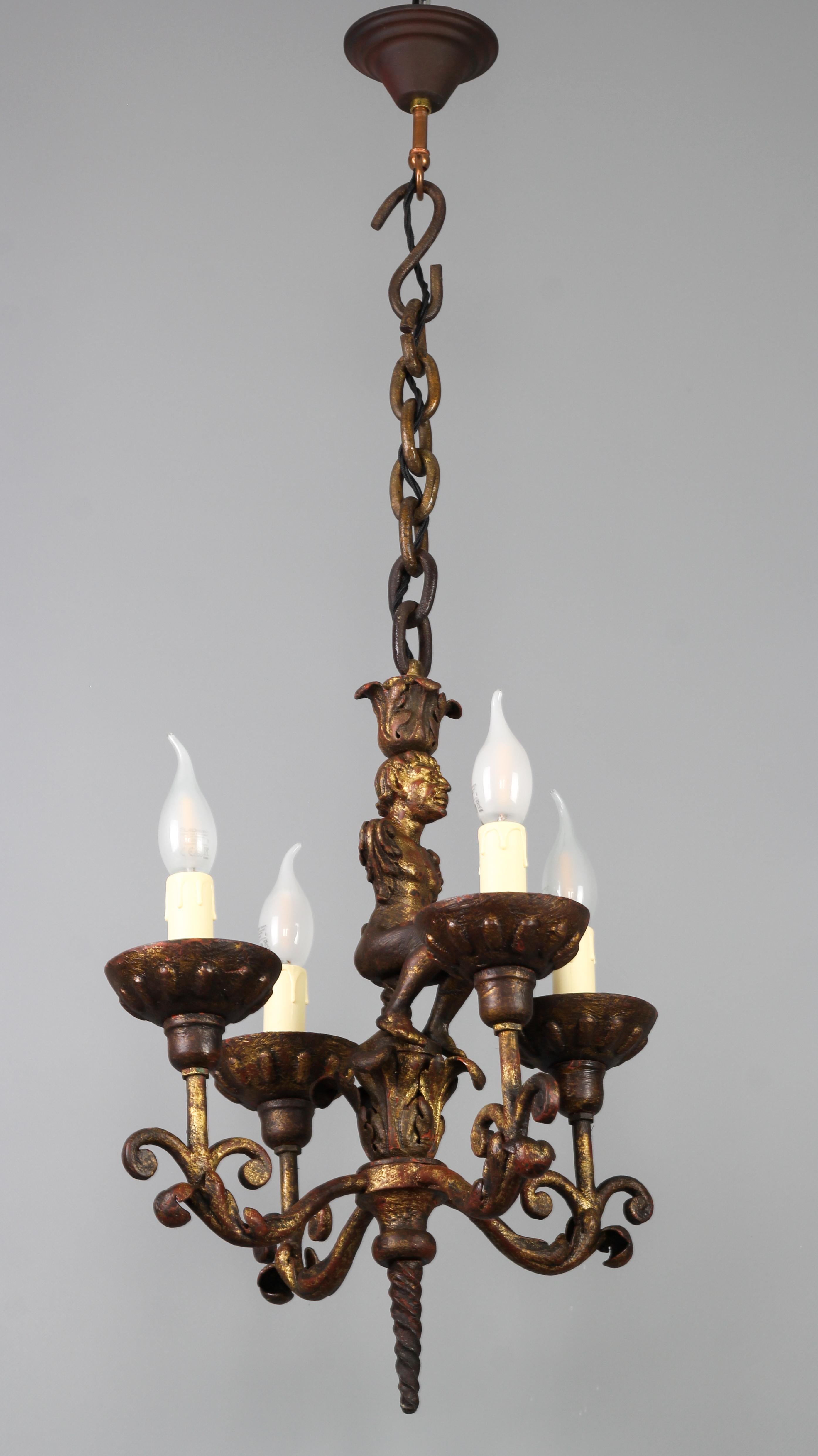 Antiker schmiedeeiserner vierflammiger figuraler Kronleuchter im Barockstil, Frankreich, Ende 19. Früher ein Kerzenleuchter, wurde er im 20. Jahrhundert elektrifiziert.
Dieser einzigartige und beeindruckende, in Gold und Rot patinierte,
