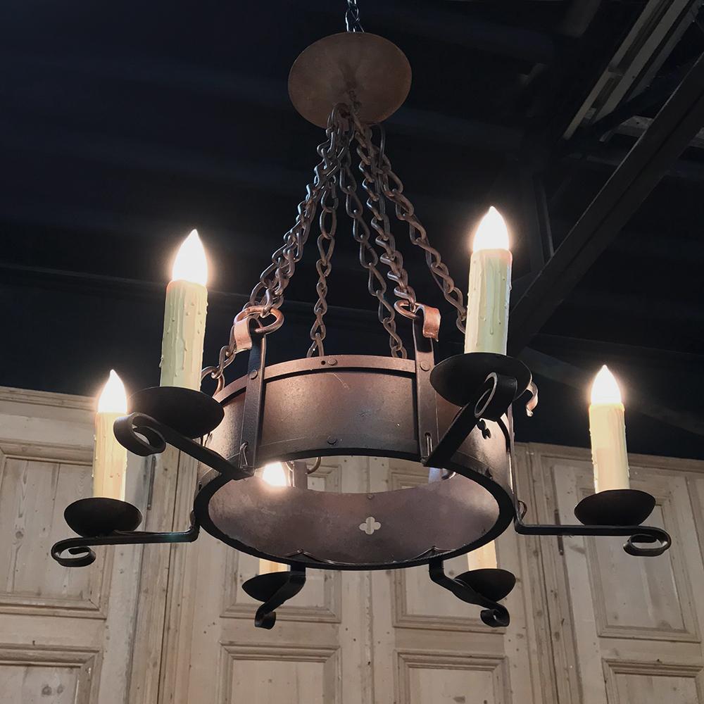 Antique Wrought Iron chandelier was hand-crafted by talented metalsmiths who were inspired by medieval examples long before the advent of electric lighting. This chandelier was originally intended for candles and has been cleverly retrofitted to