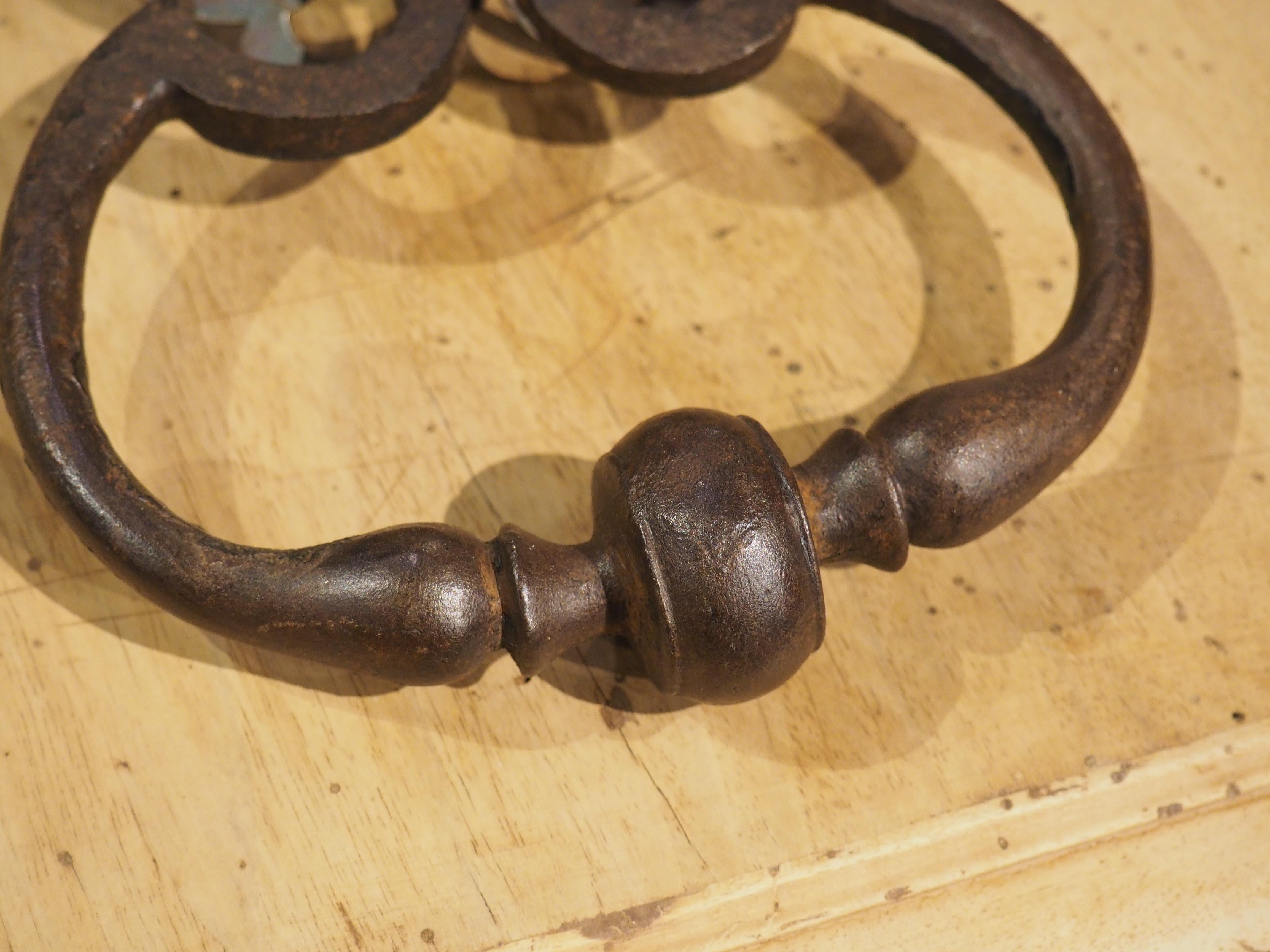 Hand-crafted in France in the 1700’s, this wrought iron door knocker features a pierced backplate in the shape of a stylized closed crown. There are small holes at the top and sides of the crown, where nails would help support the weight of the
