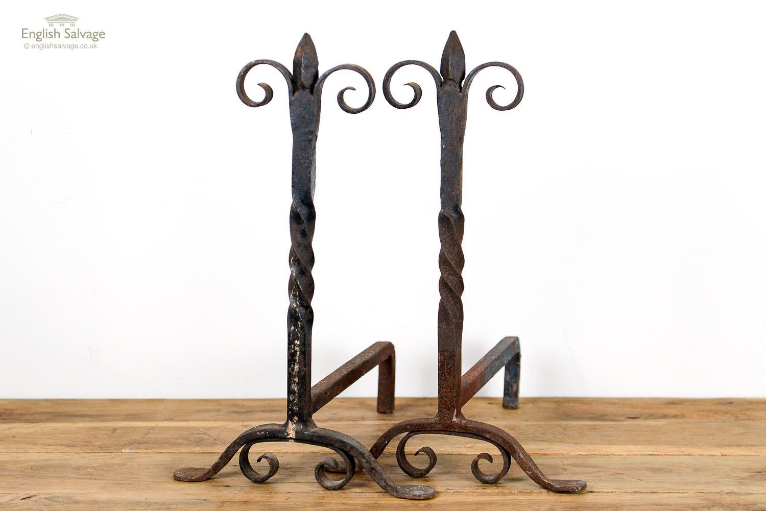Robust pair of antique wrought iron firedogs. The simple twist and scroll design with arrowhead top is enhanced by the patina formed of surface rust.