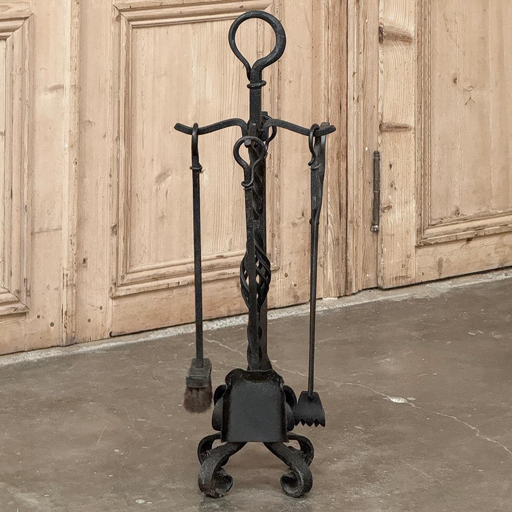 L'antico set di utensili per caminetto in ferro battuto con supporto sarà il compagno perfetto del tuo focolare.  Realizzato meticolosamente a mano in ferro rovente, presenta un manico ad anello affusolato con fusto a spirale che include una