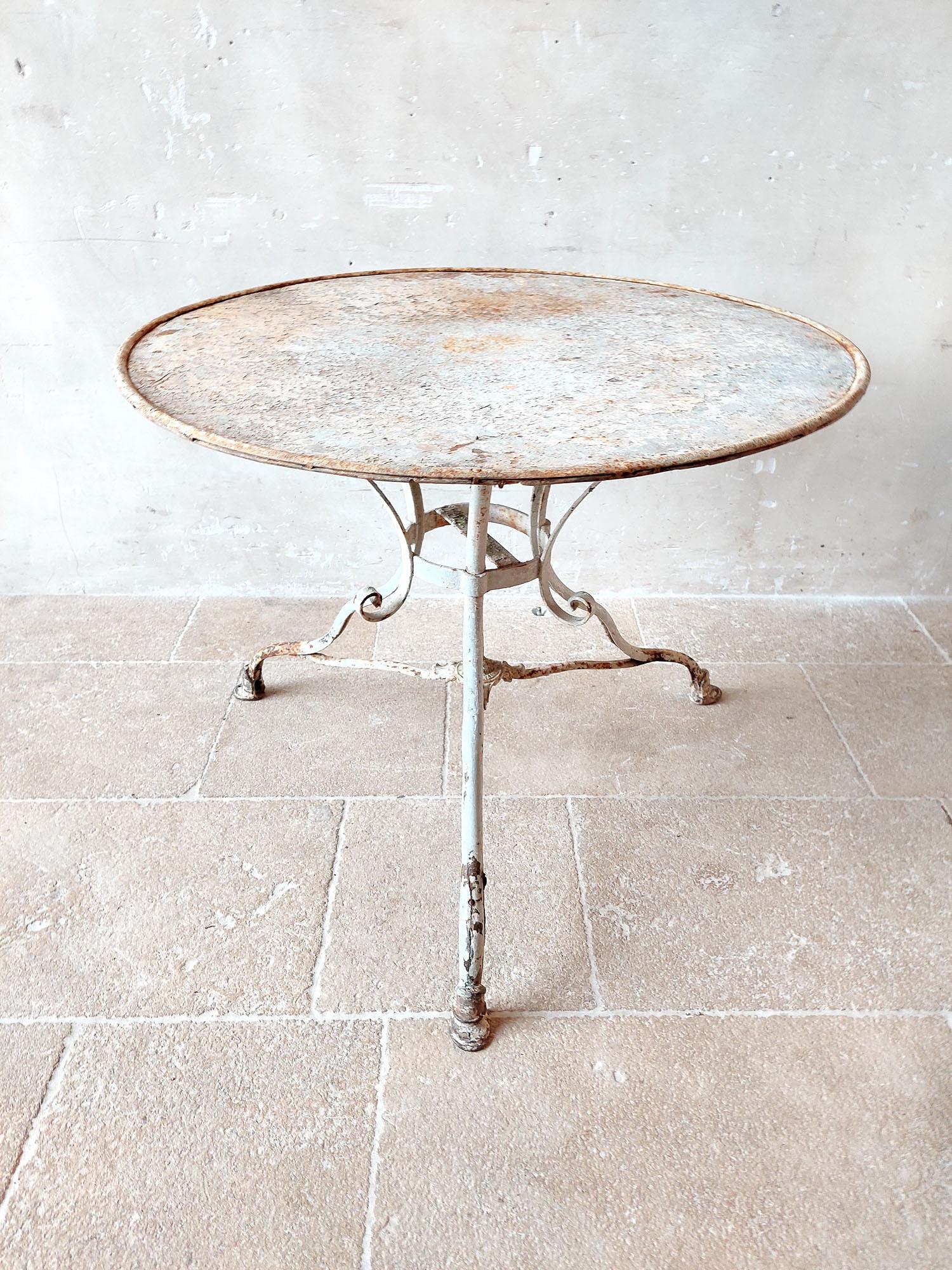 Ancienne table de jardin Grassin à Arras en fer forgé avec pieds en fonte, avec patine d'origine blanc-gris.

h 73 x diamètre 91,5 cm