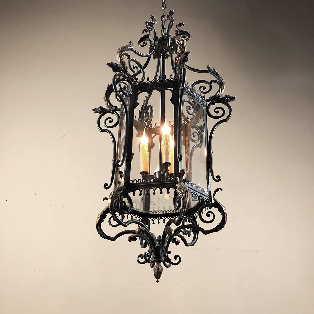 Antique French wrought iron lantern is a marvel of the master ironworker's art! intricate scrollwork with acanthus leaves which are enhanced with antique gold provides a visual feast for the eyes. Imagine the hours of labor it took to produce such