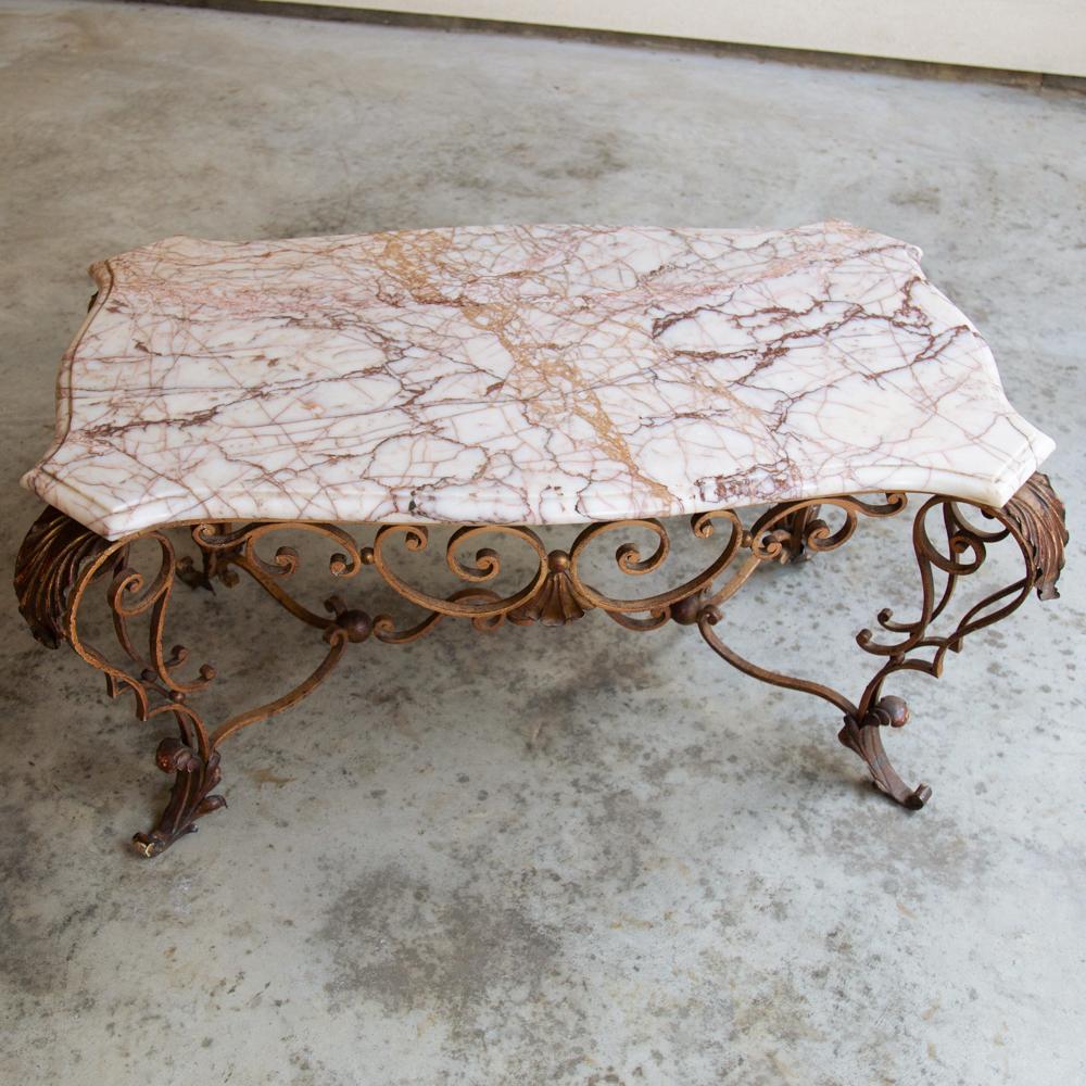Antique wrought iron and marble coffee table features a finely contoured and beveled marble top resting on an intricately scrolled wrought iron base accented with painted acanthus leaf flourishes,
circa mid-1900s.
Measures: 20 H x 32 W x 22 D.