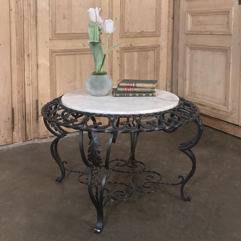 Mid-Century French wrought iron marble top coffee table not only presents the carefree elegance of a marble top, it is supported by an elaborately and expertly rendered example of the ironworker's art! Copious scrollwork appears from the top to the