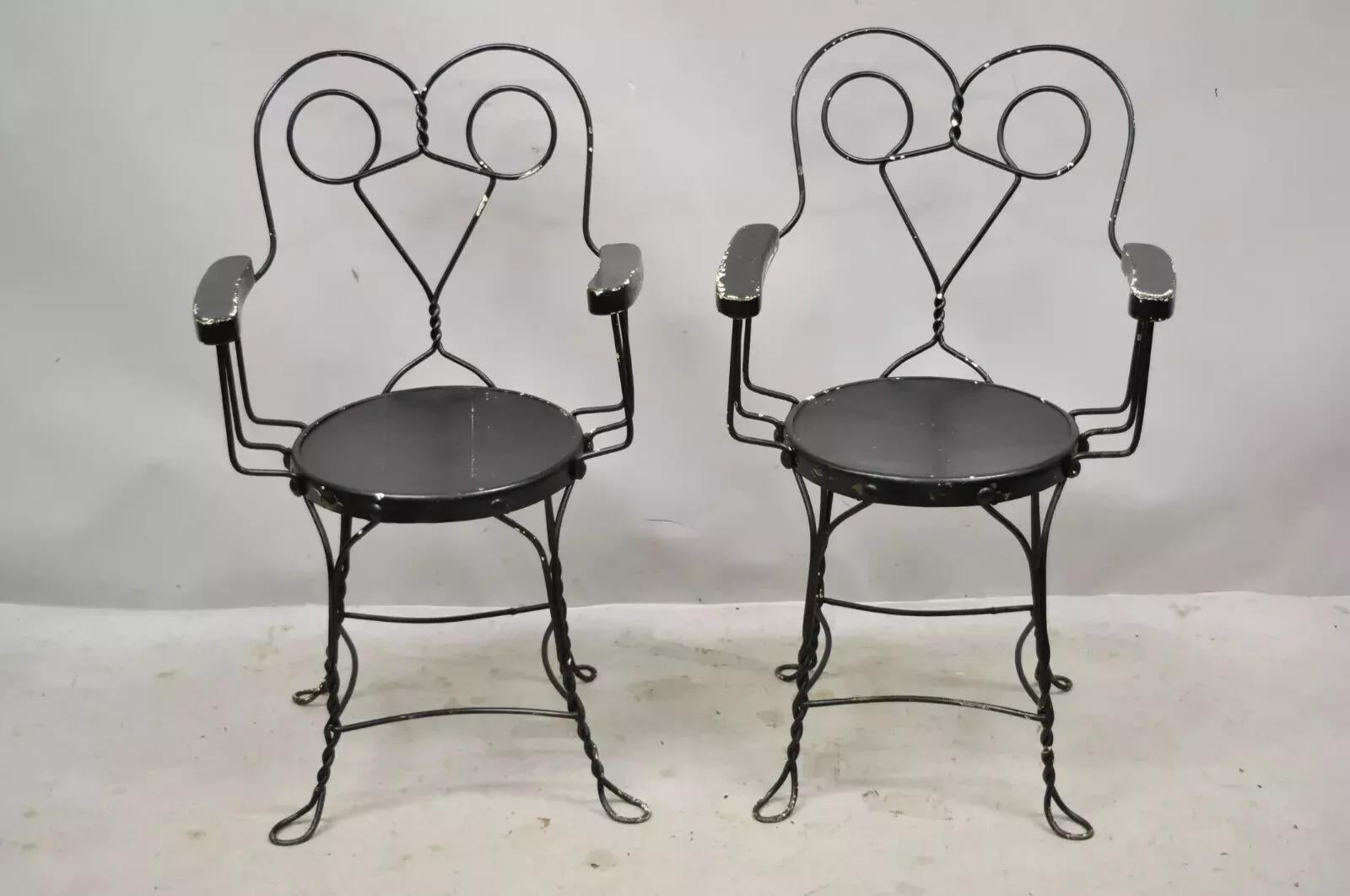 Antique Wrought Iron Twisted Metal Ice Cream Parlor Arm Chairs - a Pair. Item features wooden arm rests, wooden round seat, twisted metal frame, very nice antique pair. Circa Late 19th Century. Measurements: 35
