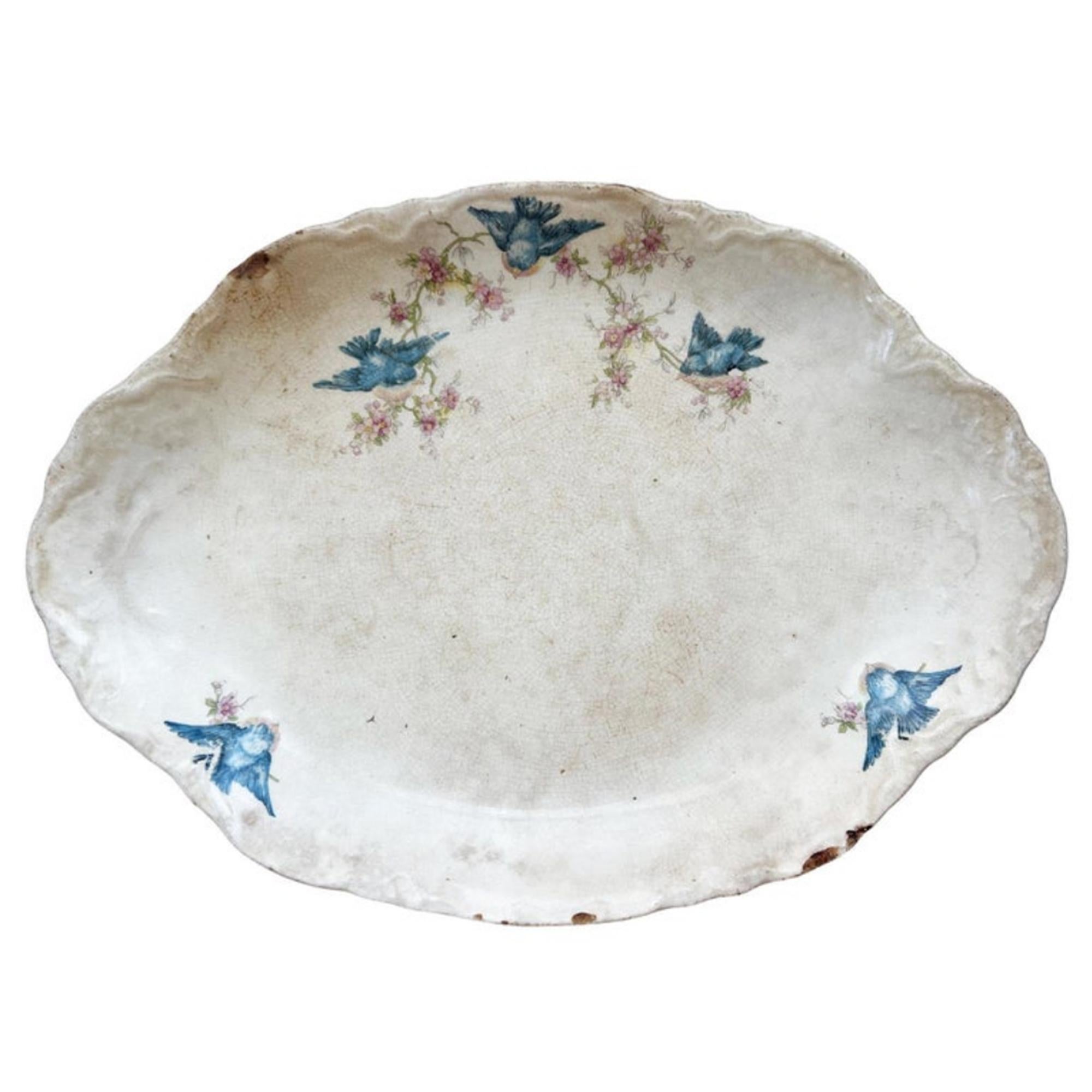 This charming antique W.S. George Radisson Bluebird Platter is the epitome of early 20th-century American ironstone romanticism. Featuring sweet sky-blue songbirds perched among delicate pink blossoms, this oval serving platter carries that coveted