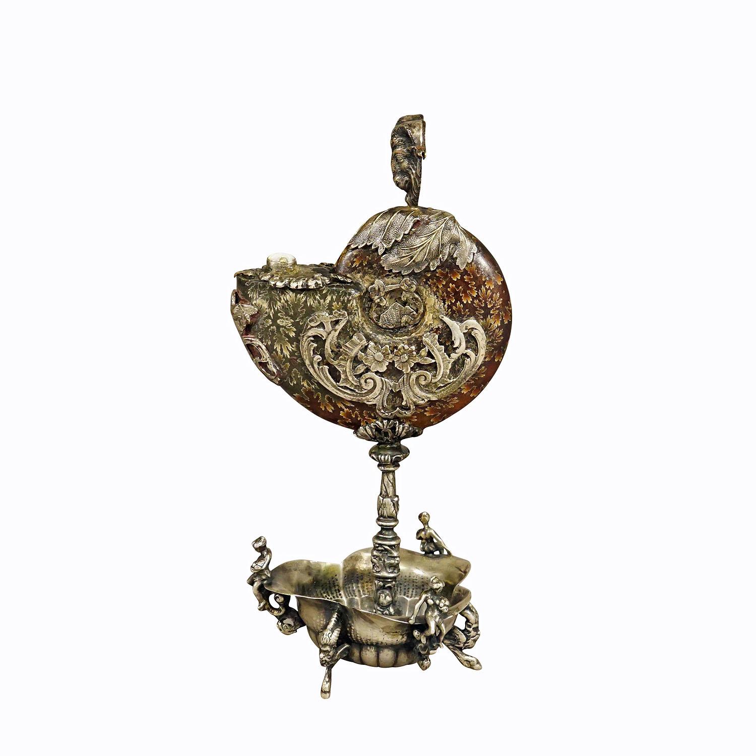 Antique Wunderkammer Installation of a Ammonite with Silver Mounting

An antique Wunderkammer installation of an ammonite cephalopod shell fossil with silver mounting. The elaborately worked silver mount features a goat, cupid, gargoiles and a