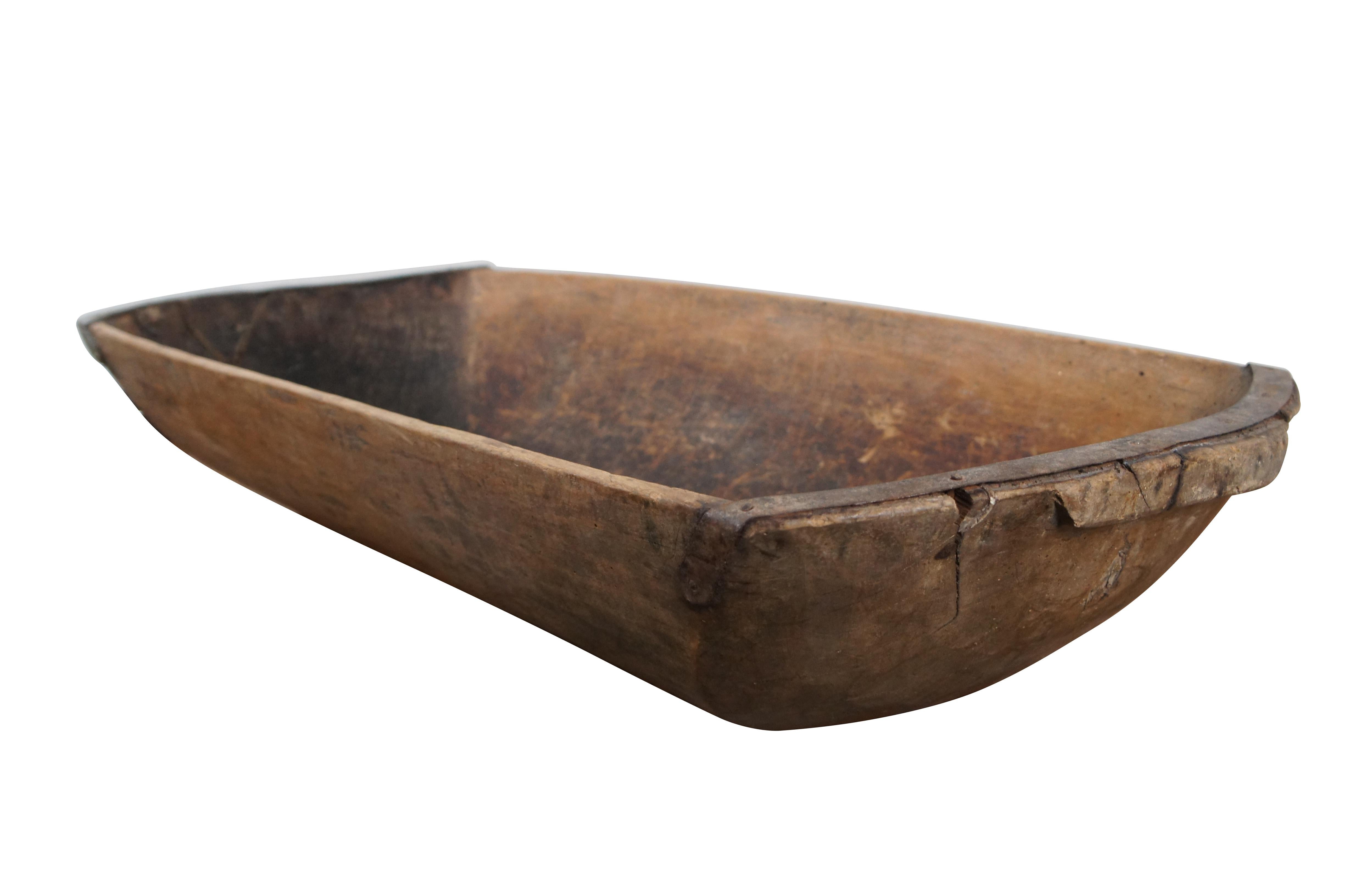 Antique, hand hewn, oversized country dough bowl / trencher featuring a rounded rectagular shape, tapered base, and iron banding / patches on the ends.

Dimensions:
44