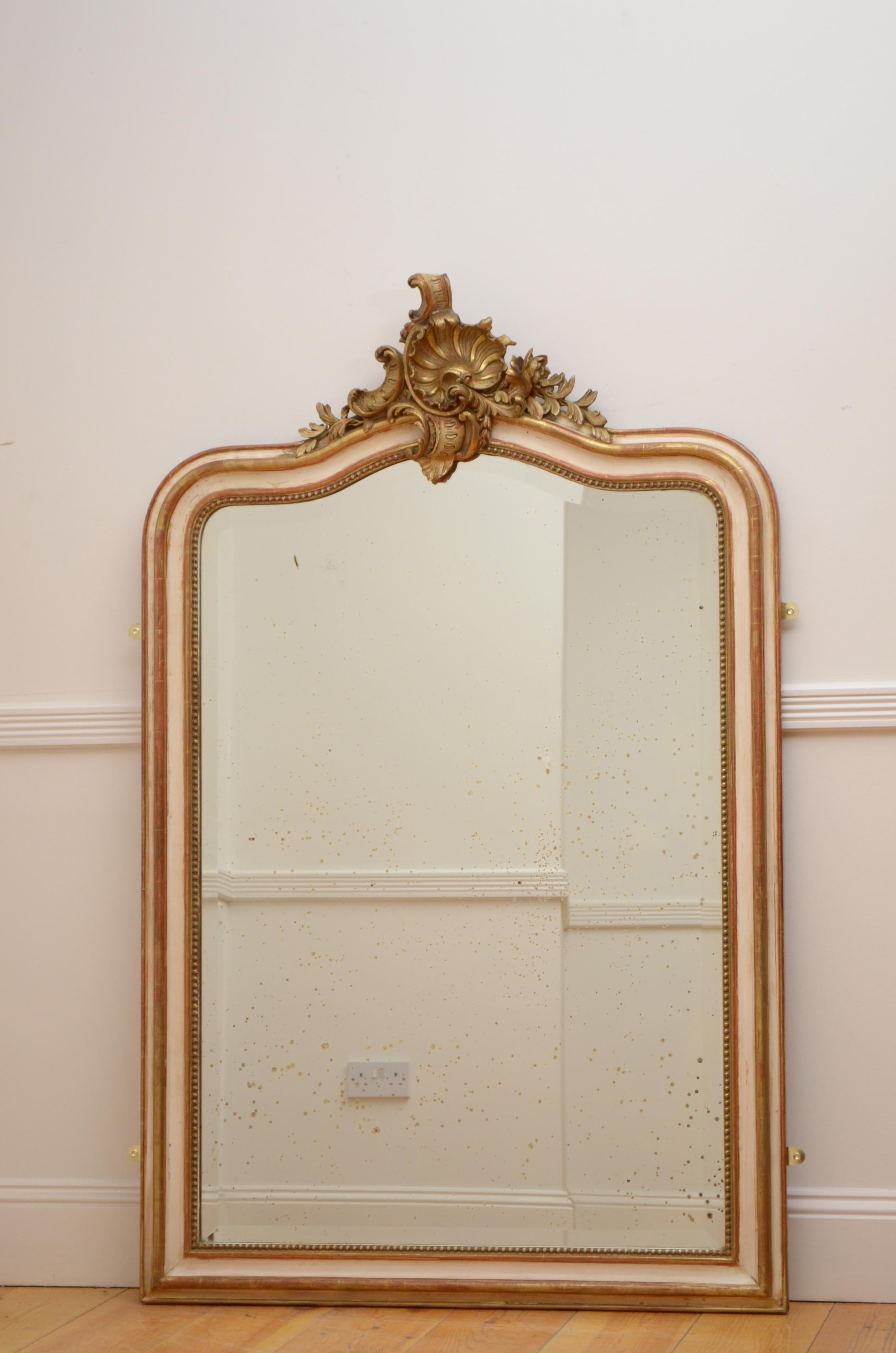 K0467 beautiful French, cream and gold leaf wall mirror, having original bevelled edge glass with some foxing in beaded and shaped frame with shell and floral centre crest to the top. This antique mirror retains its original glass, original gold