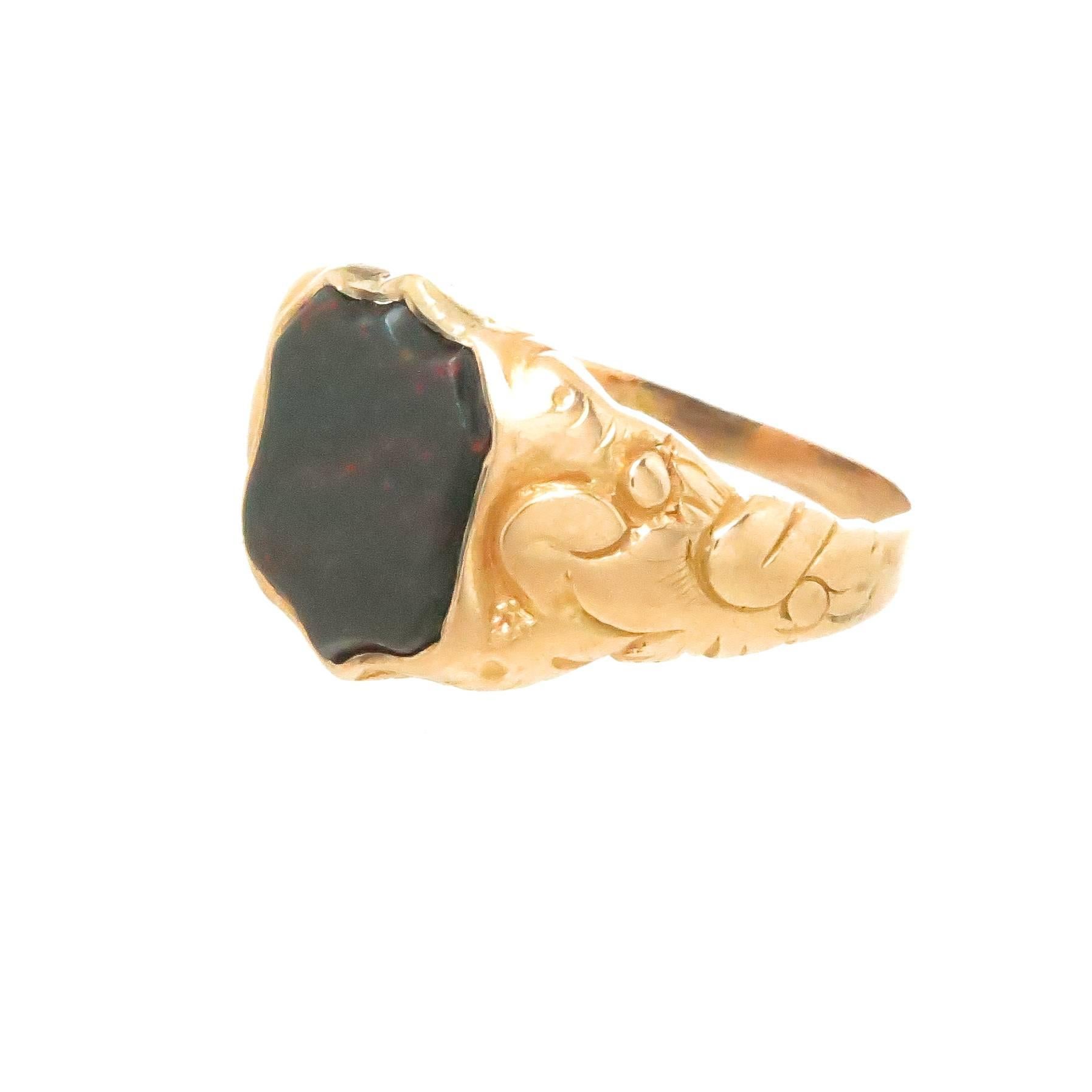 Circa 1880 - 1900 15K Yellow Gold Ring, having high relief floral design work and centrally set with a shield shape Blood Stone measuring 3/8 X 3/8 inch. Having partial English stamps, finger size 6 3/4.