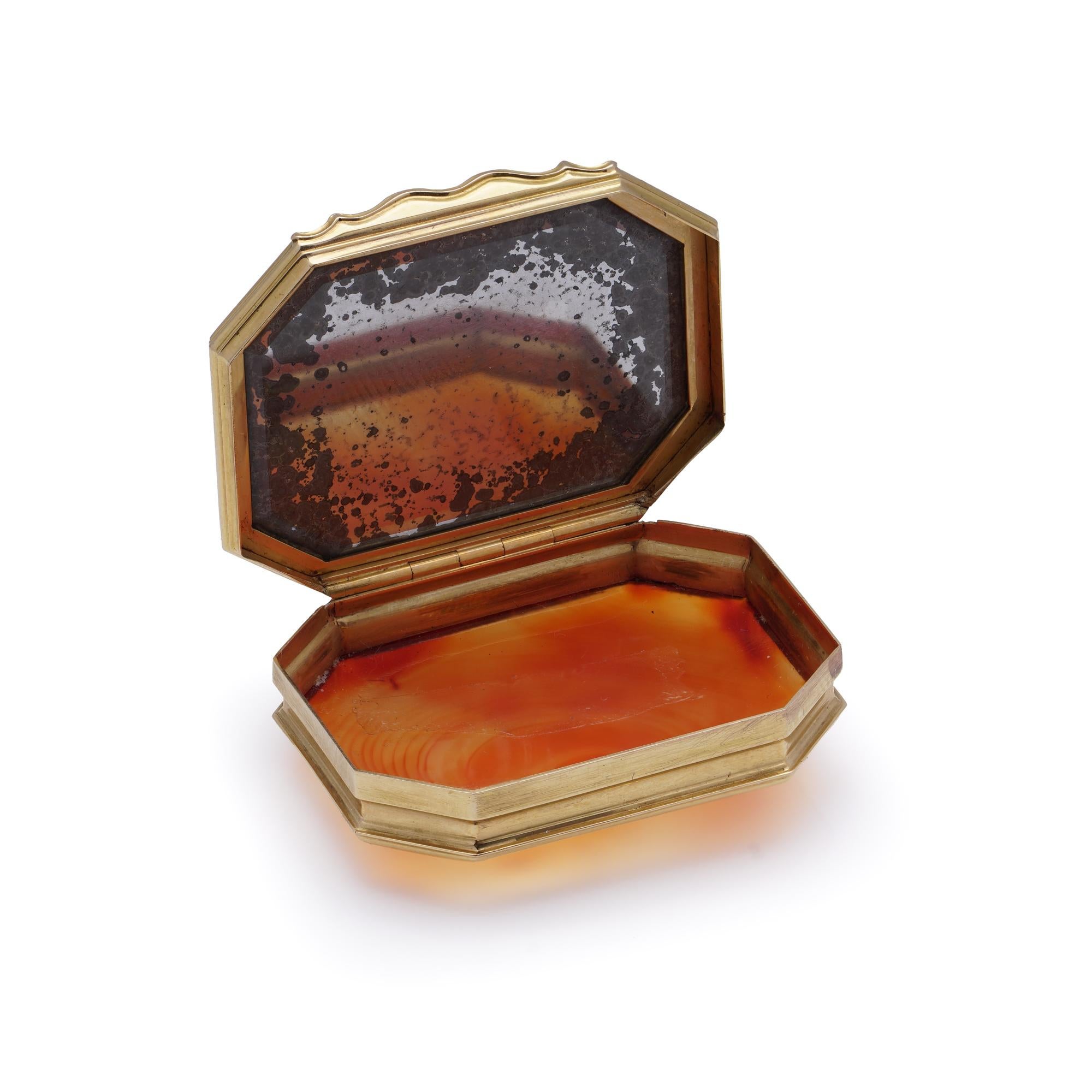 Antike Schnupftabakdose aus 18-karätigem Gelbgold mit einem Karneolstein, der in eine verschnörkelte Umrandung eingefasst ist. 

MATERIAL: Die aus 18-karätigem Gelbgold gefertigte Schatulle zeigt ein verziertes, vom Rokoko inspiriertes