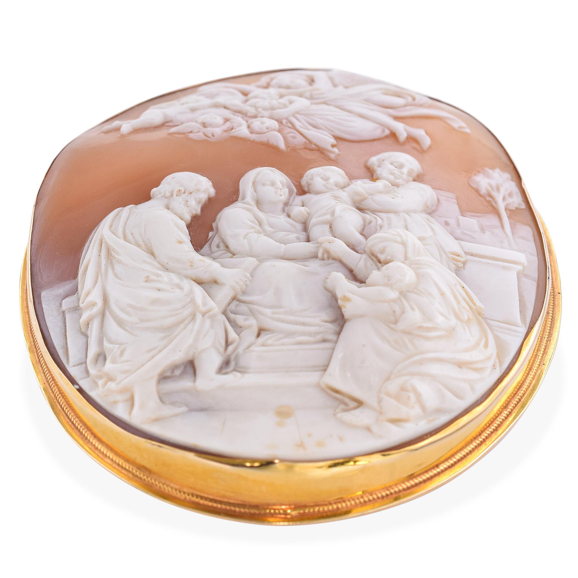 Questo antico ciondolo a spilla presenta un cammeo in conchiglia splendidamente intagliato che raffigura la Sacra Famiglia con il giovane Gesù e Giovanni Battista. Incorniciato in caldo oro giallo, il pezzo irradia serenità spirituale e raffinata