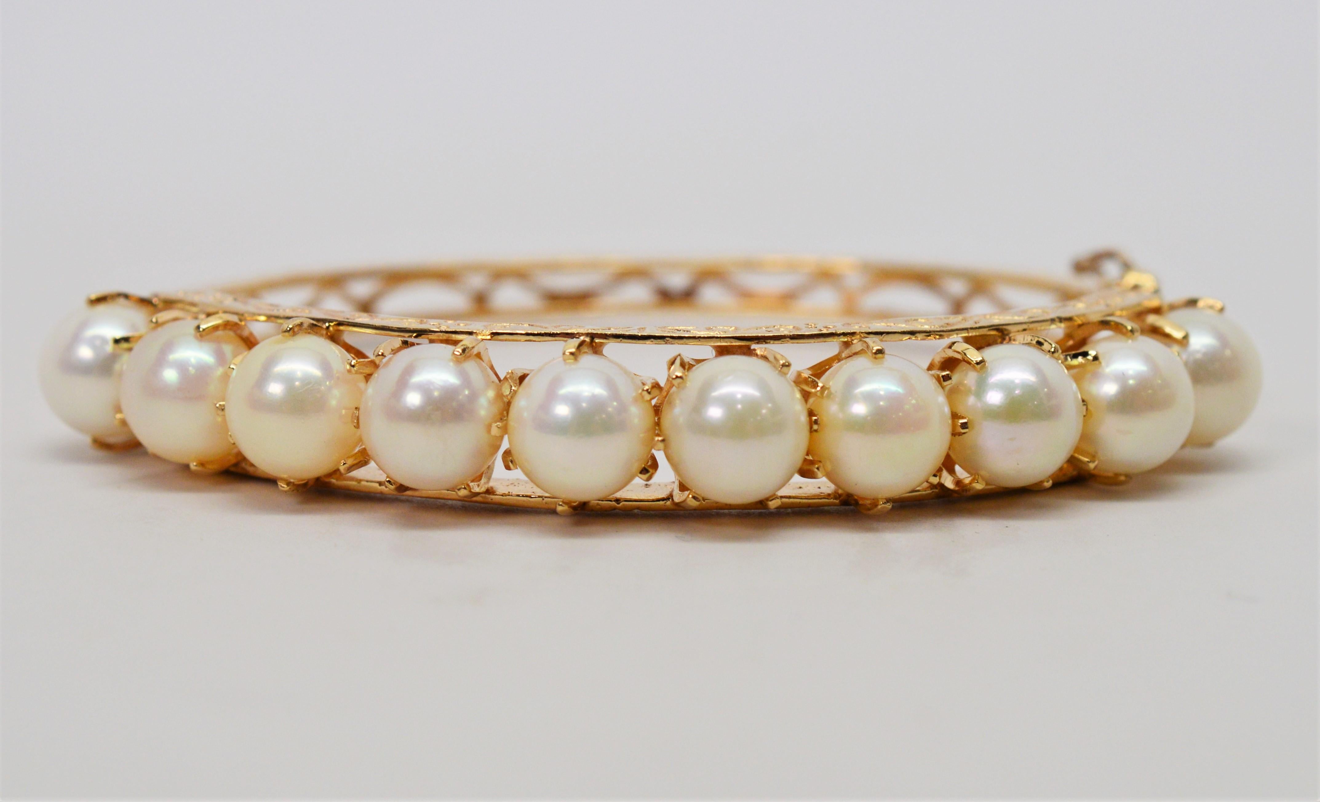 Elegantly adorned with natural Akoya Pearls, this bracelet is beautifully crafted in fourteen karat yellow gold with a lattice style back band and has engraved detailing top and bottom. The 7.7 mm round pearls are AAA and crown the wrist.  In a
