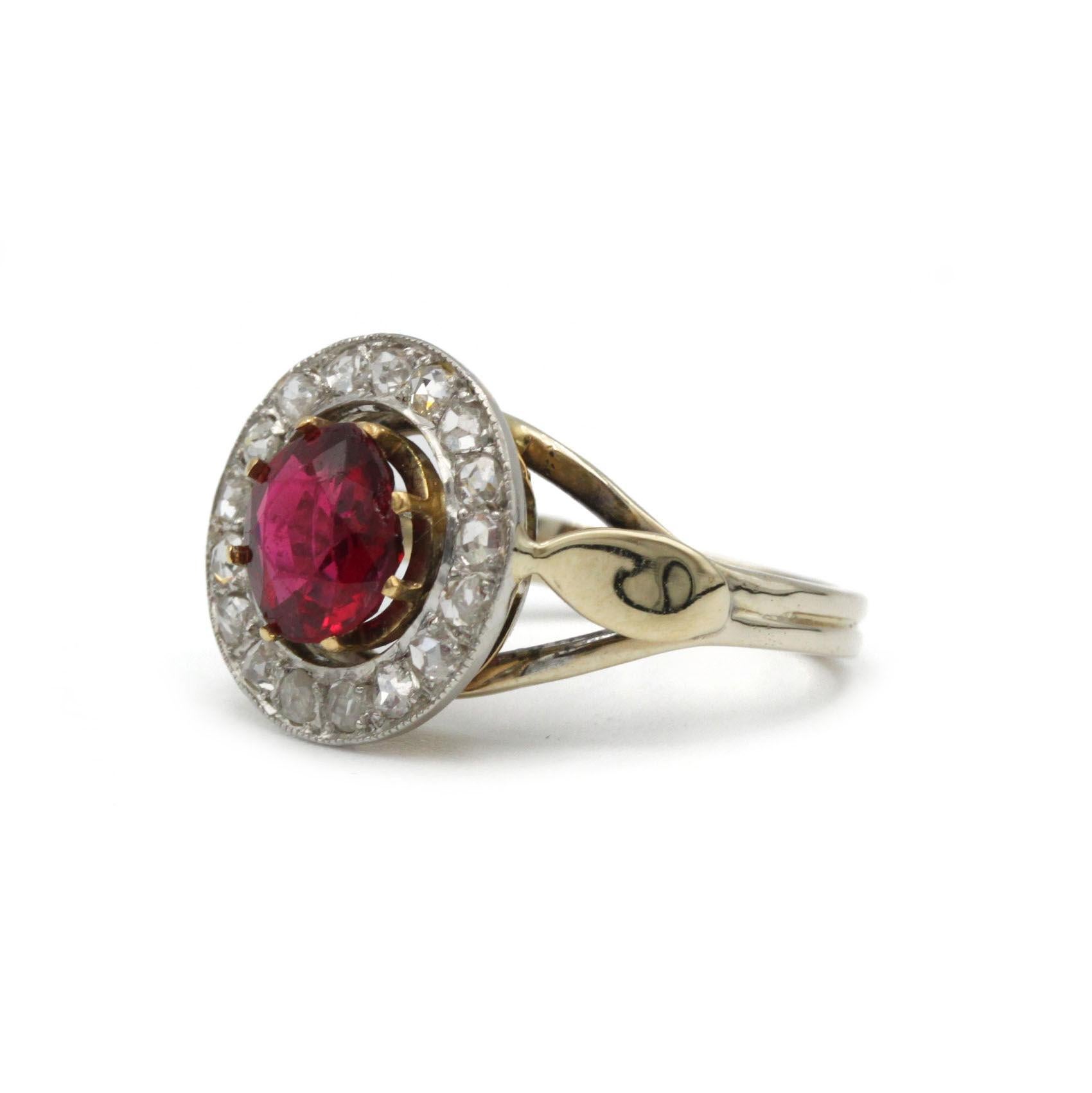 Cette exquise bague française ancienne est réalisée en or jaune 18 carats et met en valeur un magnifique grenat rouge foncé pesant environ 2 carats. La pierre précieuse centrale est magnifiquement entourée d'un halo de 17 diamants taillés en rose