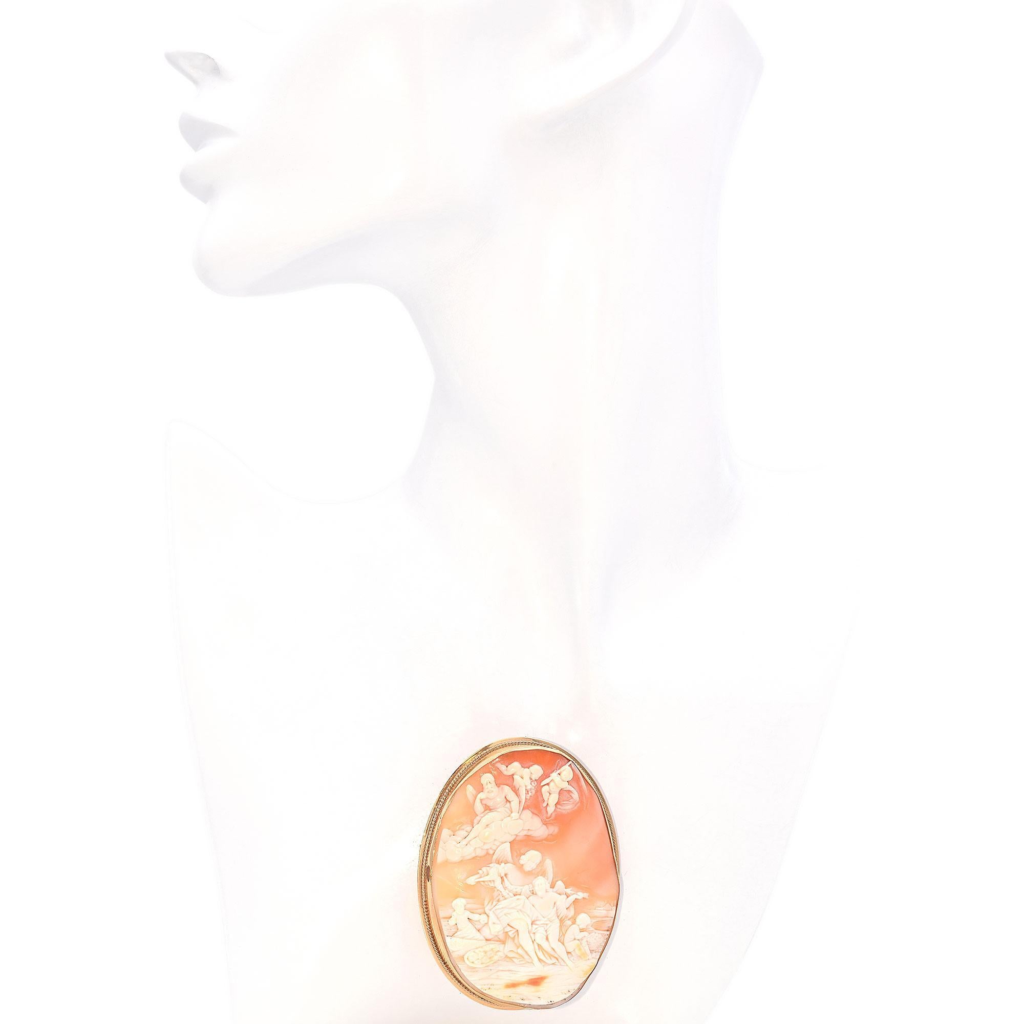 This Victory Cameo Brooch, intricately carved with a detailed scene of cherubs and winged figures are set in a warm yellow gold frame. The cameo's delicate craftsmanship is highlighted by the soft gradient of the shell, creating a striking contrast.