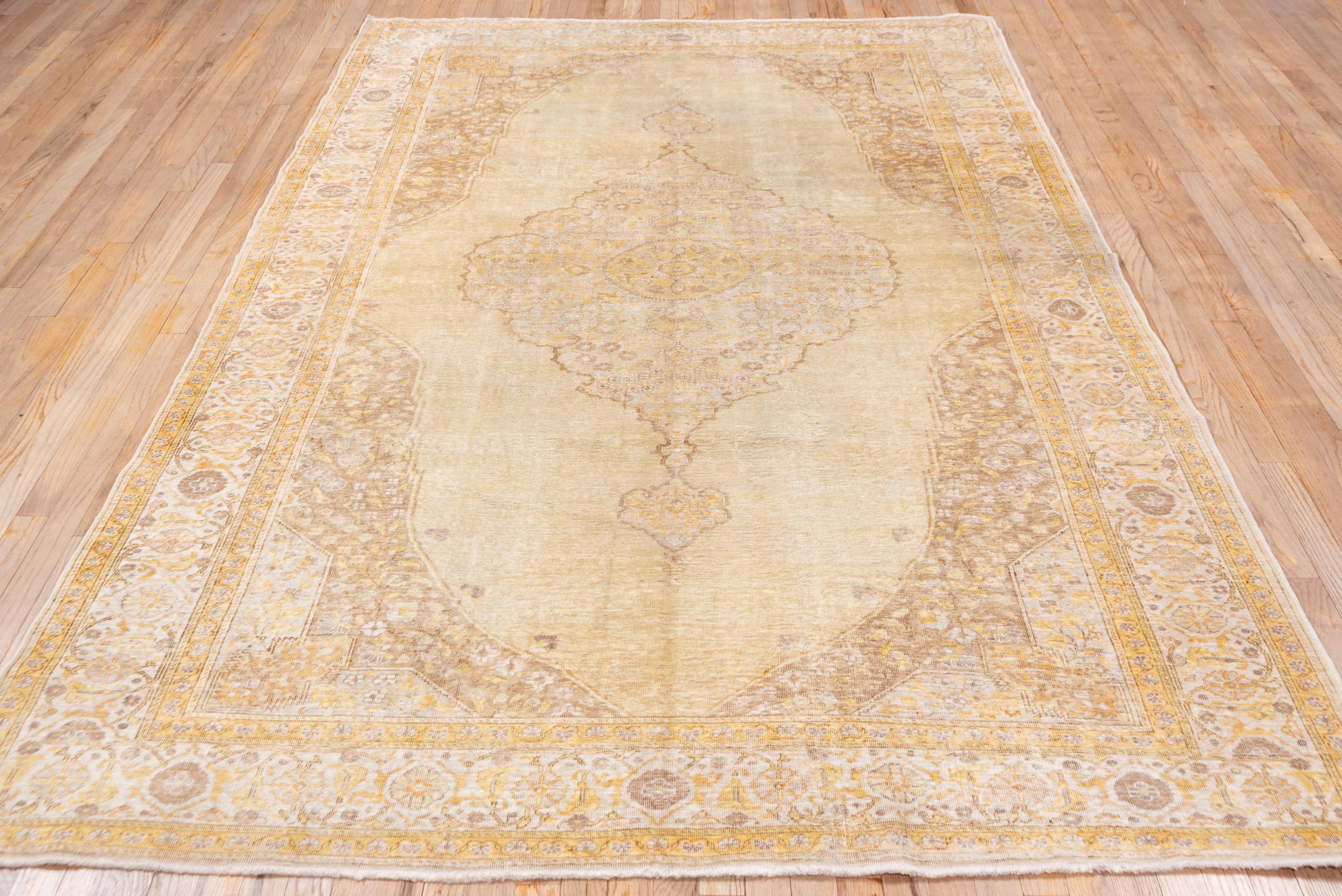 This Persian-style carpet shows a scalloped and pendanted cream and straw medallion on a straw-sand cartouche-shaped open field, set within rust-brown abrashed extended rosette accented corners. Straw-lemon accents. Cream main border and lemon-straw