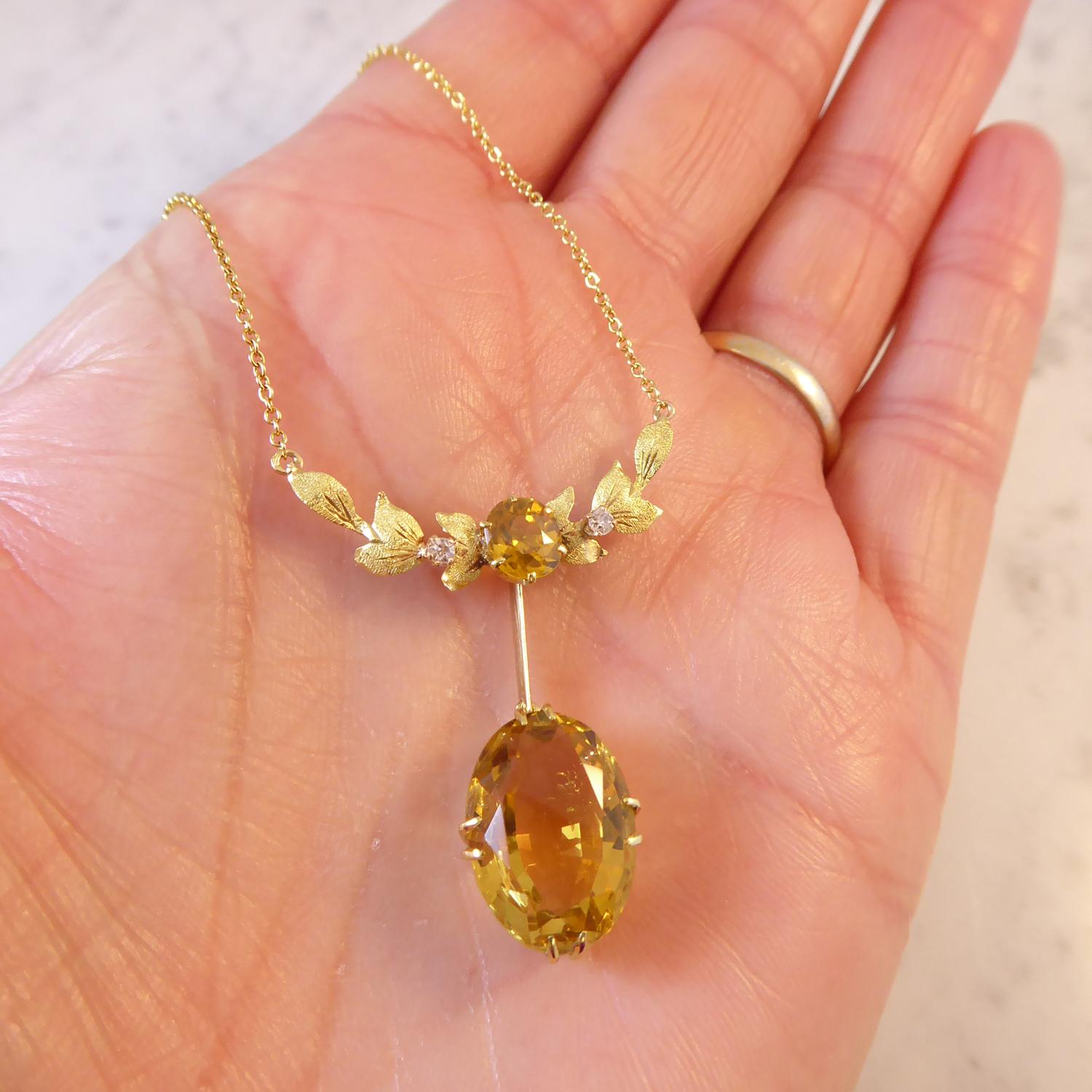 An antique necklace circa 1900 with yellow zircon and diamond set centrepiece.  Consisting of a curved, yellow, knife-edged bar with applied matt texture foliate designed panels and centring on a cushion-shaped, mixed cut yellow zircon measuring