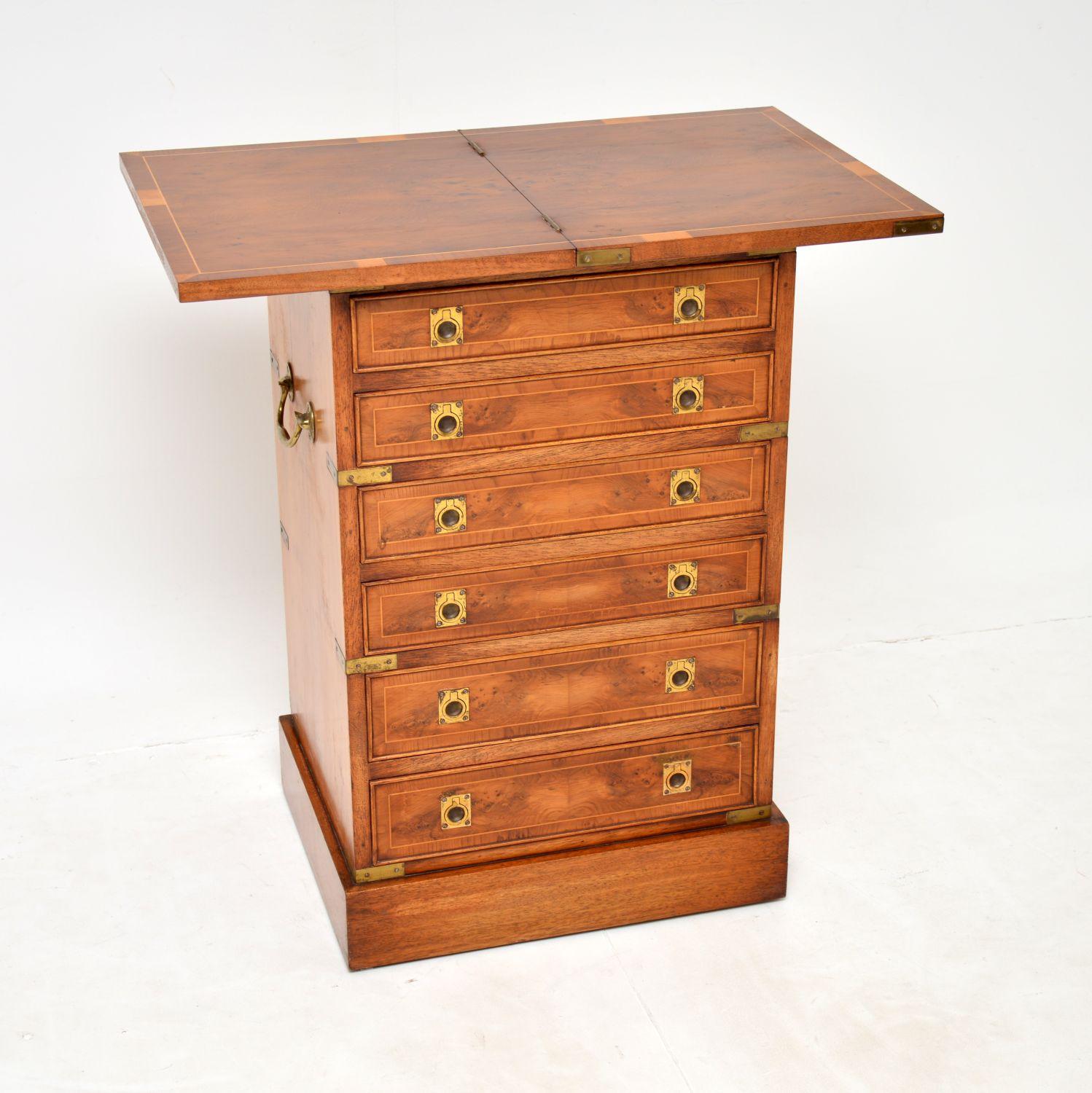 A stunning antique military Campaign style chest of drawers in yew wood. This was made in England & dates from around the 1930’s period.
It is of exceptional quality, with an unusual top that spins round and unfolds to double in size. This chest