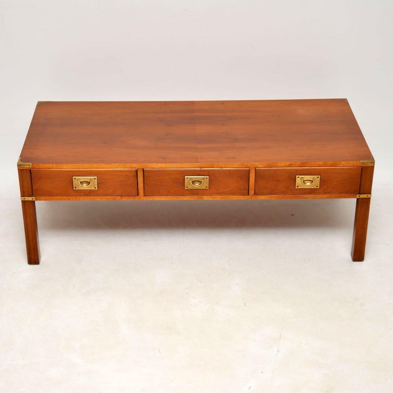 Large yew wood coffee table in the antique Campaign style dating from around the 1950s period & in good condition. It has brass military inset handles & corner fittings on the back & front. There are three drawers on the front & three dummy drawers