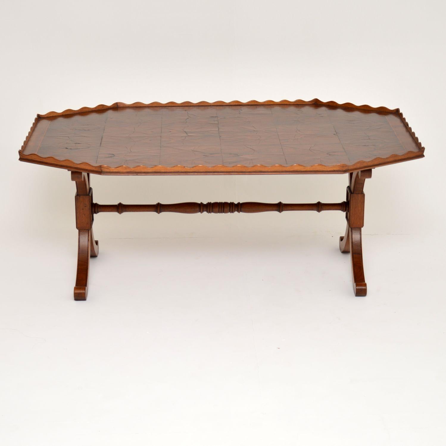 Antique yew wood and oyster veneer coffee table in good original condition and with loads of character. The top has a pie crust raised edge and there are many sections of oyster wood panels surrounded by yew wood cross banding. It sits on ‘X’ framed