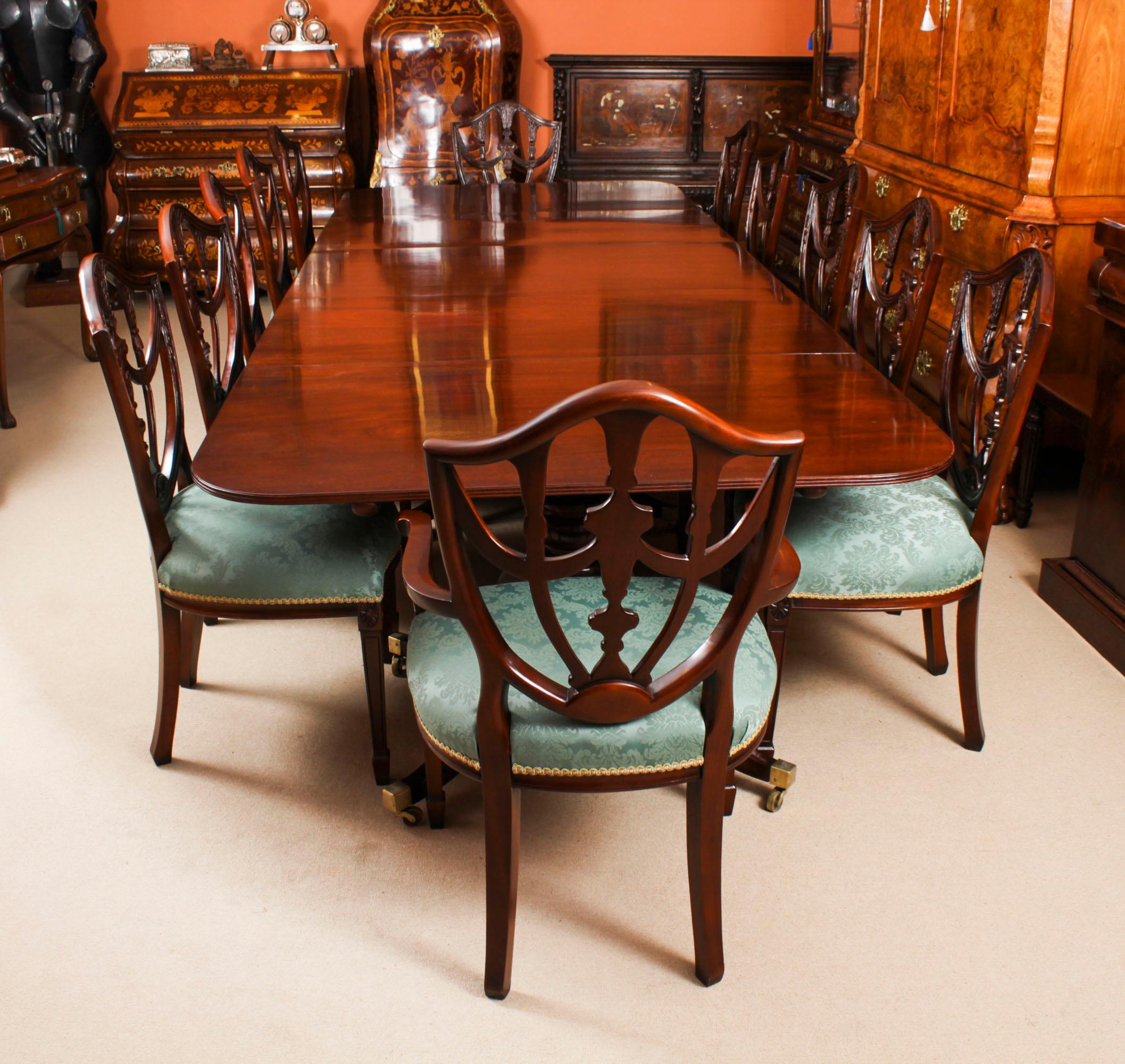 This is an elegant antique Regency dining table circa 1820 in date and twelve Federal Revival shield back dining chairs dating from the mid 20th century.

The table features elegant simplicity, with straight, unbroken surfaces and lines.  It has two