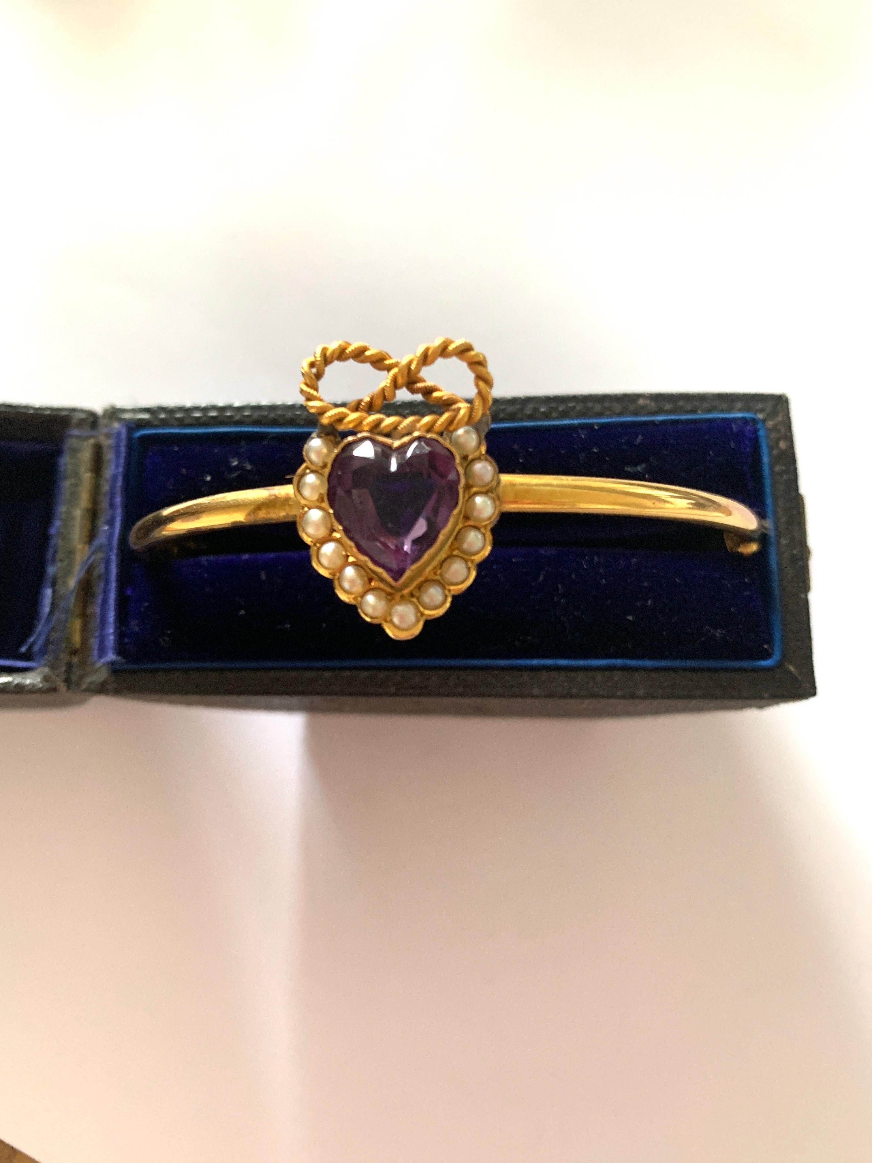 Antique Victorian Circa late 1800's
9ct Gold Sweet heart Bracelet
decorated with a heart shaped amethyst stone 
surrounded by freshwater seed pearls
Finished by a beautiful rope bow.

Supplied in Box shown. - possibly the original box !

Bangle