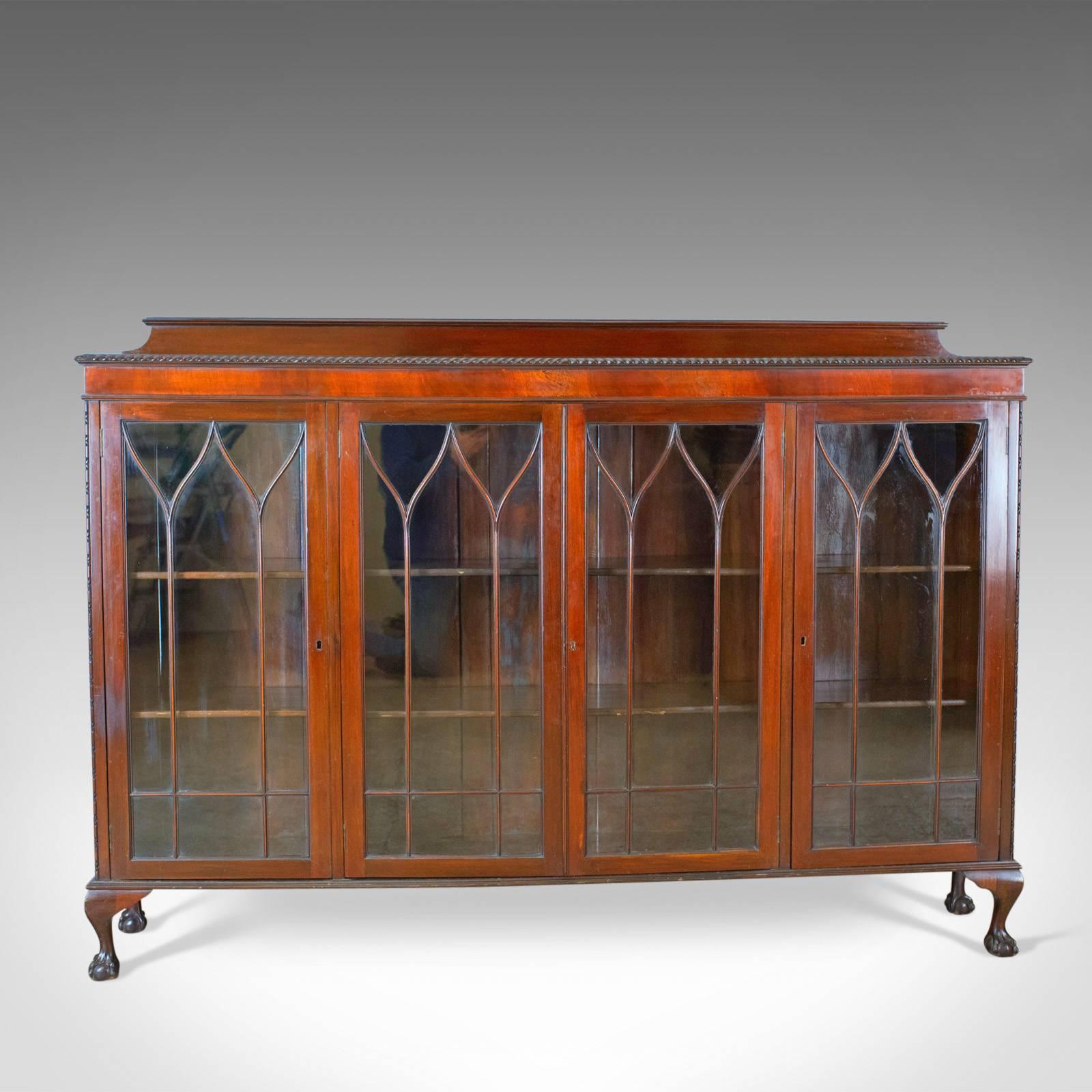 This is an antique glazed bookcase, a long English, Edwardian, mahogany cabinet with Gothic overtones dating to circa 1910.

Classic English styling with Gothic overtones
In select mahogany displaying grain interest
Desirable aged patina with a