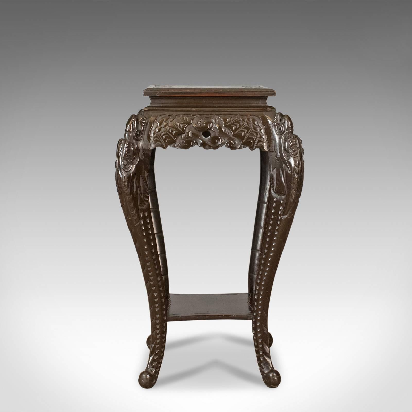 This is an antique plant stand, a carved Chinese side table, torchere or pedestal in hardwood dating to the early 20th century, circa 1910.

Profusely carved with a dark, wax, polished finish
Classic oriental styling in good proportion
Useful