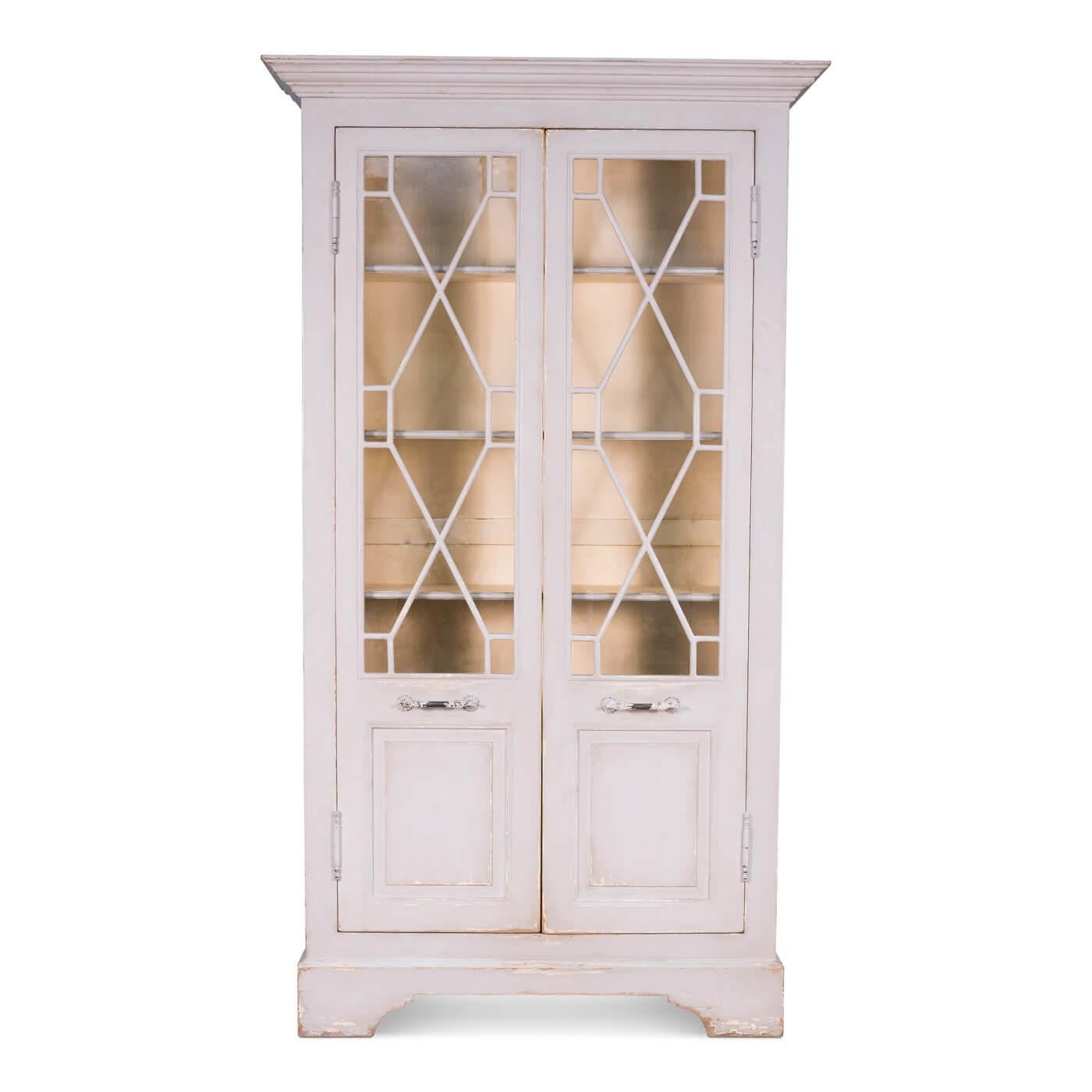 Antiqued farmhouse style painted cabinet. A beautiful and functional cabinet that can be used for display and storage. The exterior is painted in a soft grey, beautiful fretwork glass doors reveal the interior which is painted in light butter yellow