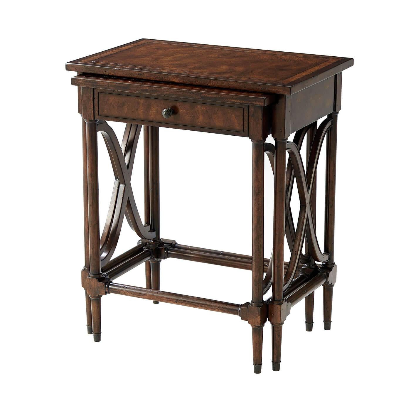 A nest of two antiqued mahogany tables, with crossbanded tops, turned legs with brass cappings and wavy 'X' stretchers to the sides, the smaller table fitted with a frieze drawer. Inspired by a 19th century English original.

Dimensions: 22