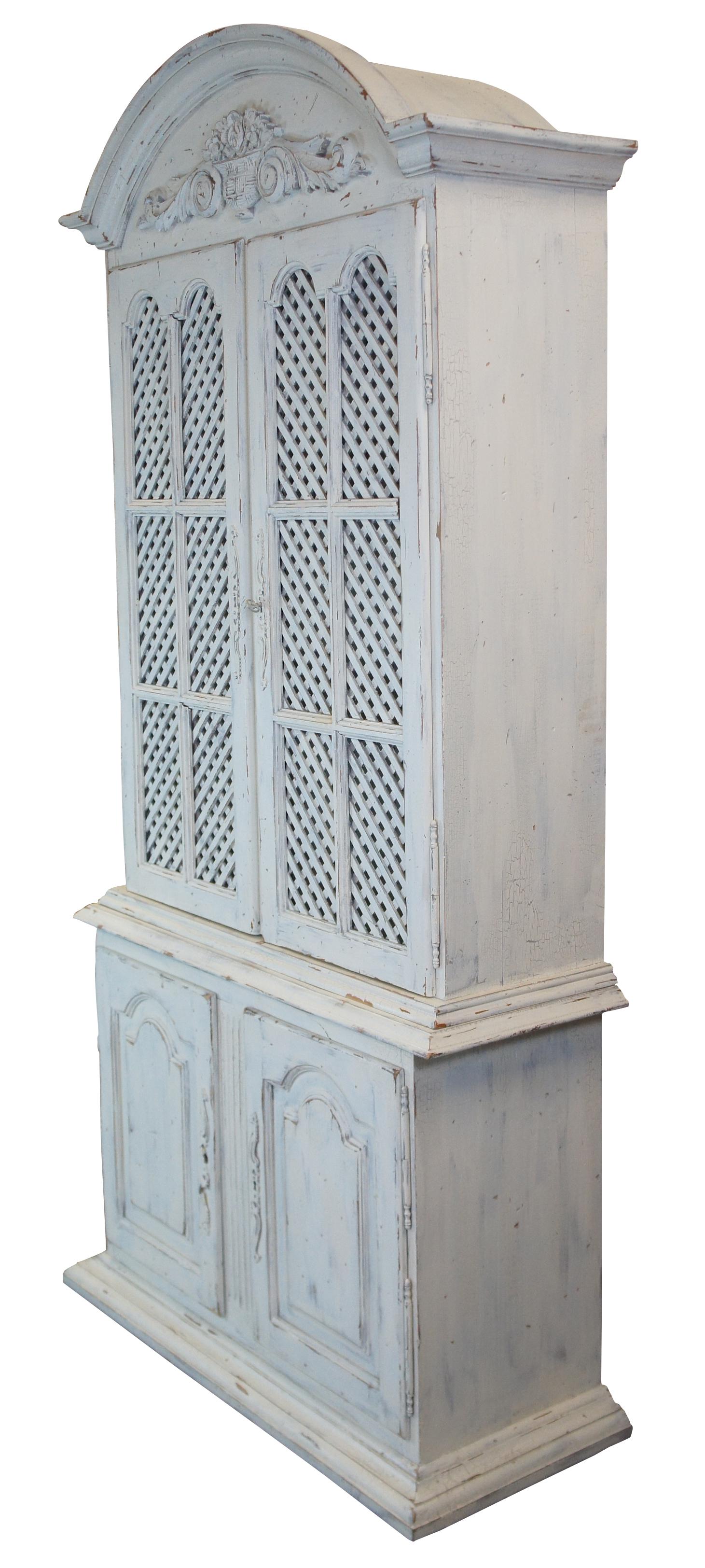 Vintage painted pine china hutch or bookcase by Garcia Imports, circa 1980s. Features a French Country or buffet deux design with lattice doors, an arched top with floral carving and plenty of shelving for storage. Includes Iron escutcheon with