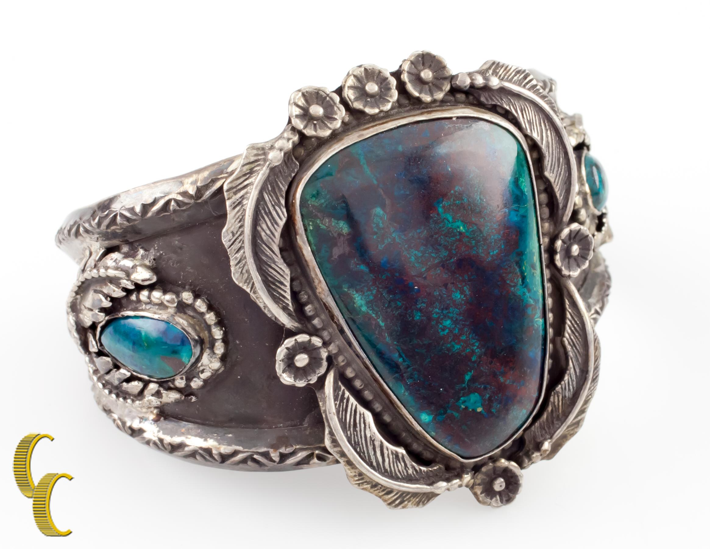 In argento sterling e con tre castoni incastonati di crisocolla blu intenso.
Delicati dettagli repousse e floreali in argento anticato.
Misura del polso: 6 pollici.
Larghezza: 2 pollici.
Metallo: argento sterling 0,925.
Peso: 76 grammi.