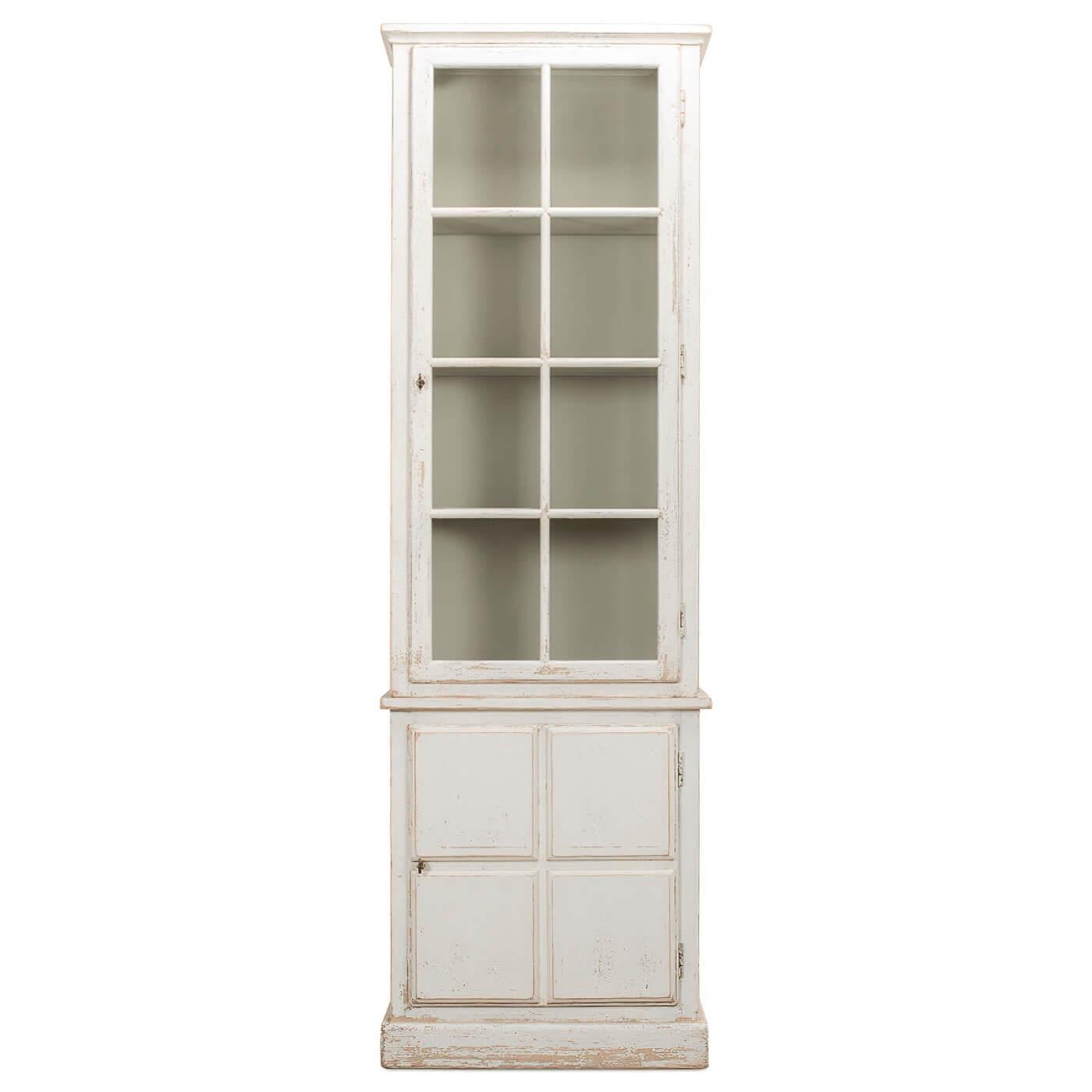 An antiqued white bookcase crafted with pine. This beautiful piece has a glass-paned upper cabinet with a painted grey interior and one lower cabinet with a door. It includes four removable shelves. This is a great piece for storage and