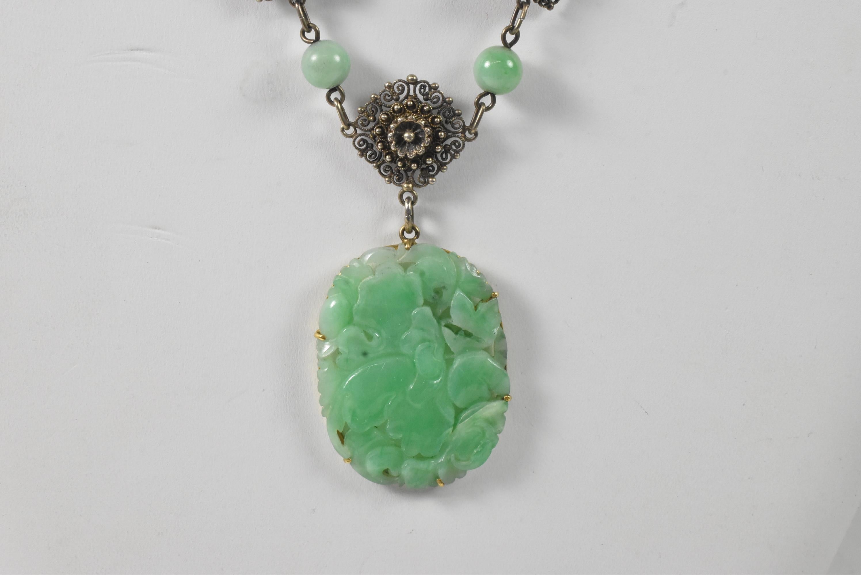 Ce magnifique collier en argent ancien est orné d'un pendentif en jade sculpté de style asiatique. La chaîne en argent massif, faite à la main, comporte des maillons inhabituels et des perles de jade. Le pendentif mesure 38 mm x 28 mm et la chaîne