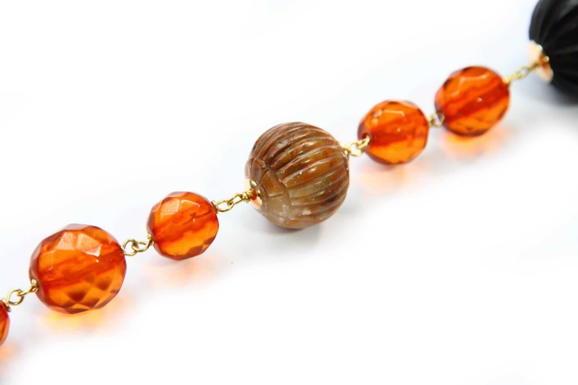 Long necklace with antiques cognac color faced amber, antiques carved jade and engrave ebony pearls,  Amethyst. This series is named Half Half as you can  see you can wear in different way and color just turn it. 18 kt Gold linked gr. 12,30.
All
