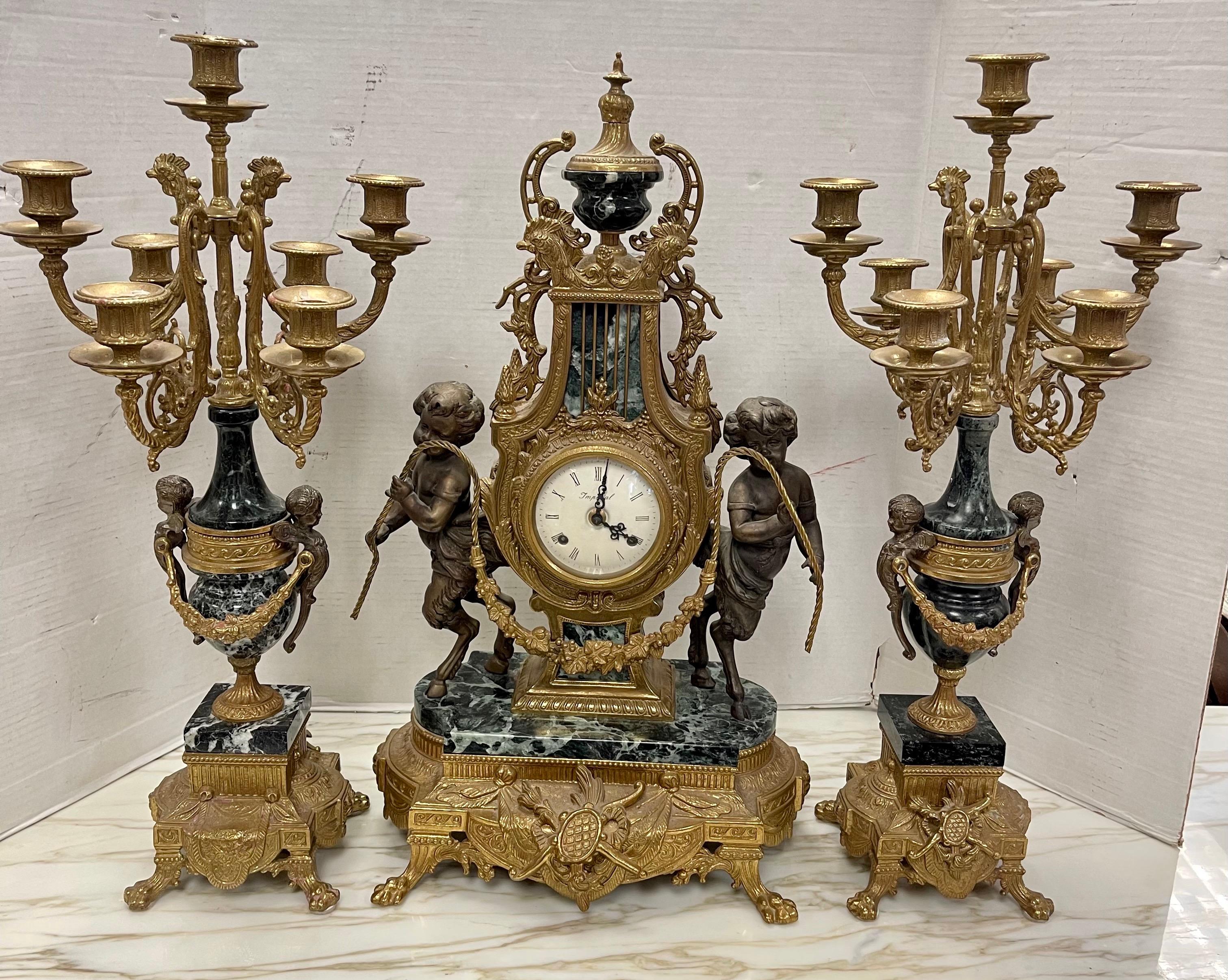 Impressive French Louis XVI style three piece garniture mantel set including clock and matching candelabras. Clock is flanked by two young fawns, half man/half goat with intricately carved marble details. The matching candelabras also feature