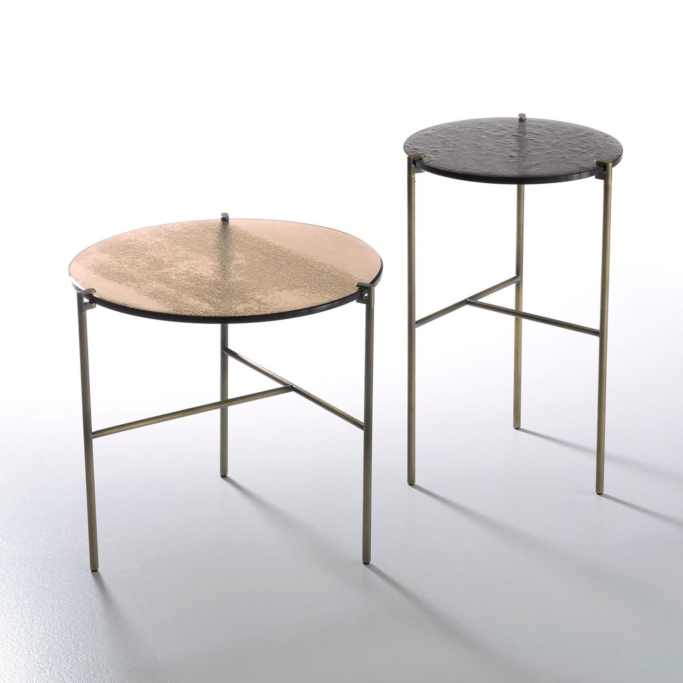 The simple and clean lines of the elegant Antitesi table make this accessory an ideal addition to your living room, lounge area or office space. With a base in satin brass and the top in three layer fused glass, in a beige tone and with a diameter