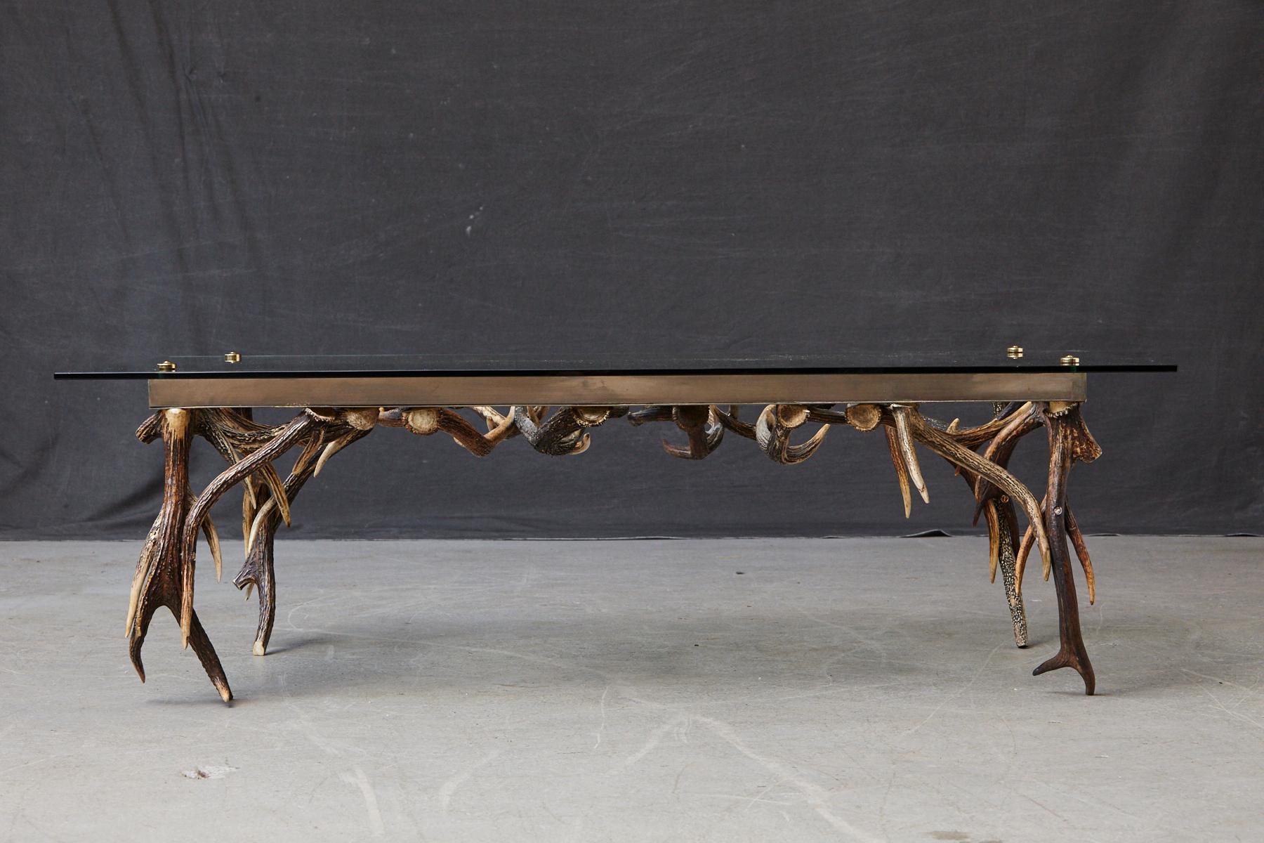 Stunning rectangular coffee table mounted on an antler base with brass frame, glass top and brass finials, 
attributed to Anthony Redmile, circa 1970s.

The antlers are in excellent condition, the brass frame has some patina, a few scratches to the