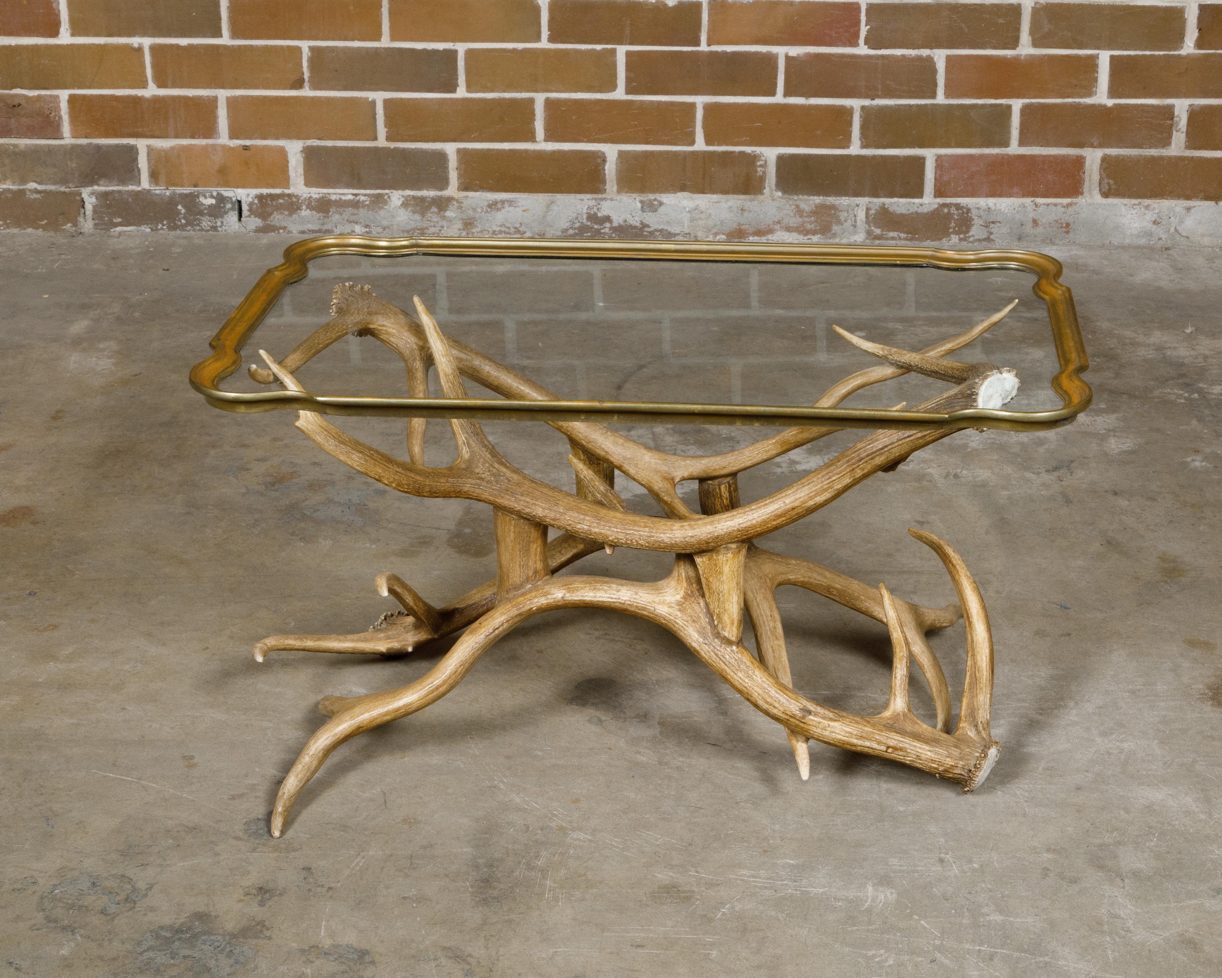 Ein amerikanischer Couchtisch aus der Mitte des Jahrhunderts mit Glasplatte und Geweihfuß. Dieser bezaubernde amerikanische Couchtisch aus der Mitte des Jahrhunderts verbindet nahtlos rustikalen Charme mit raffinierter Eleganz. Er verfügt über einen