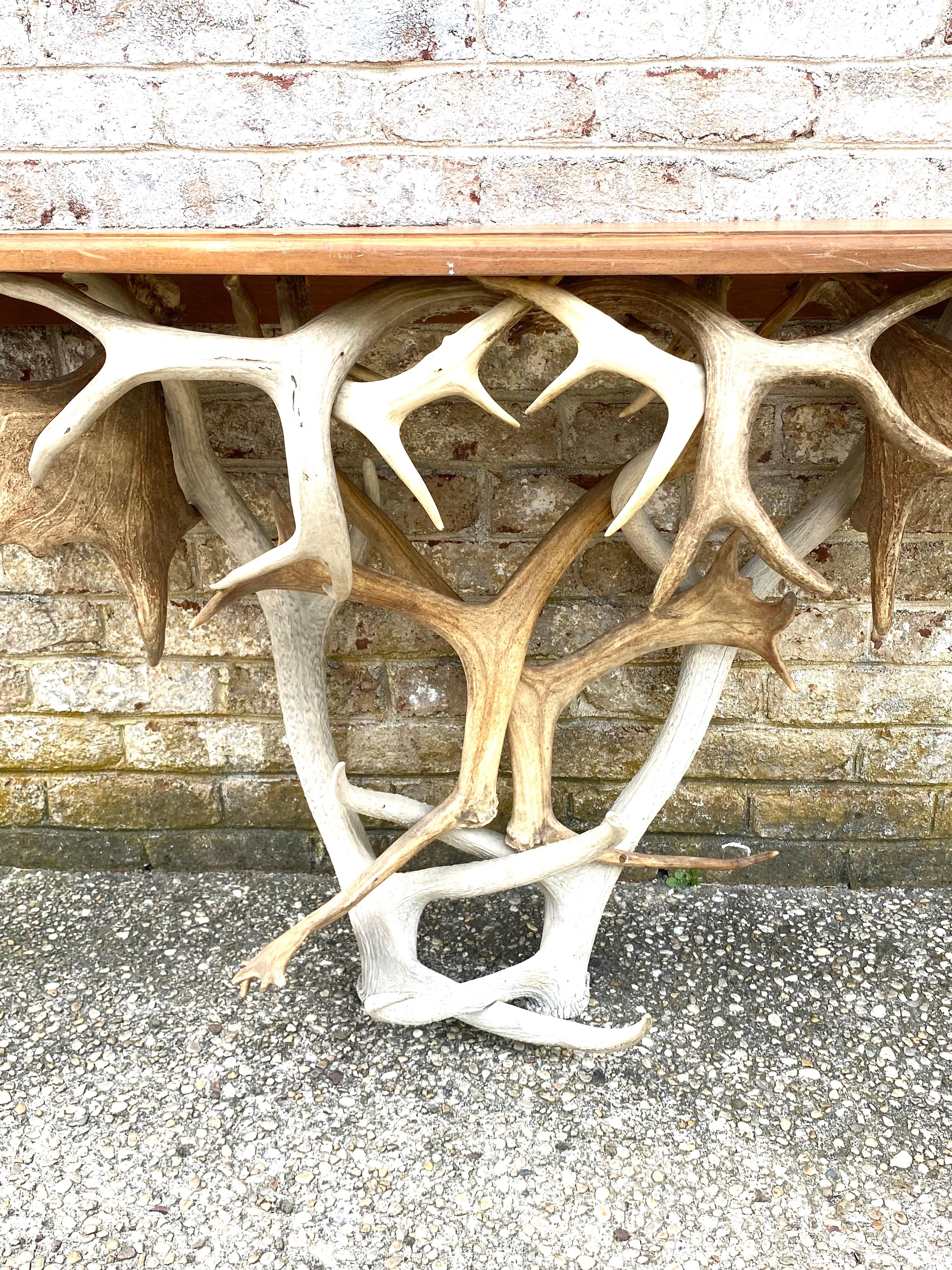 Demi-lune wood top console with base made up of deer and moose antlers....