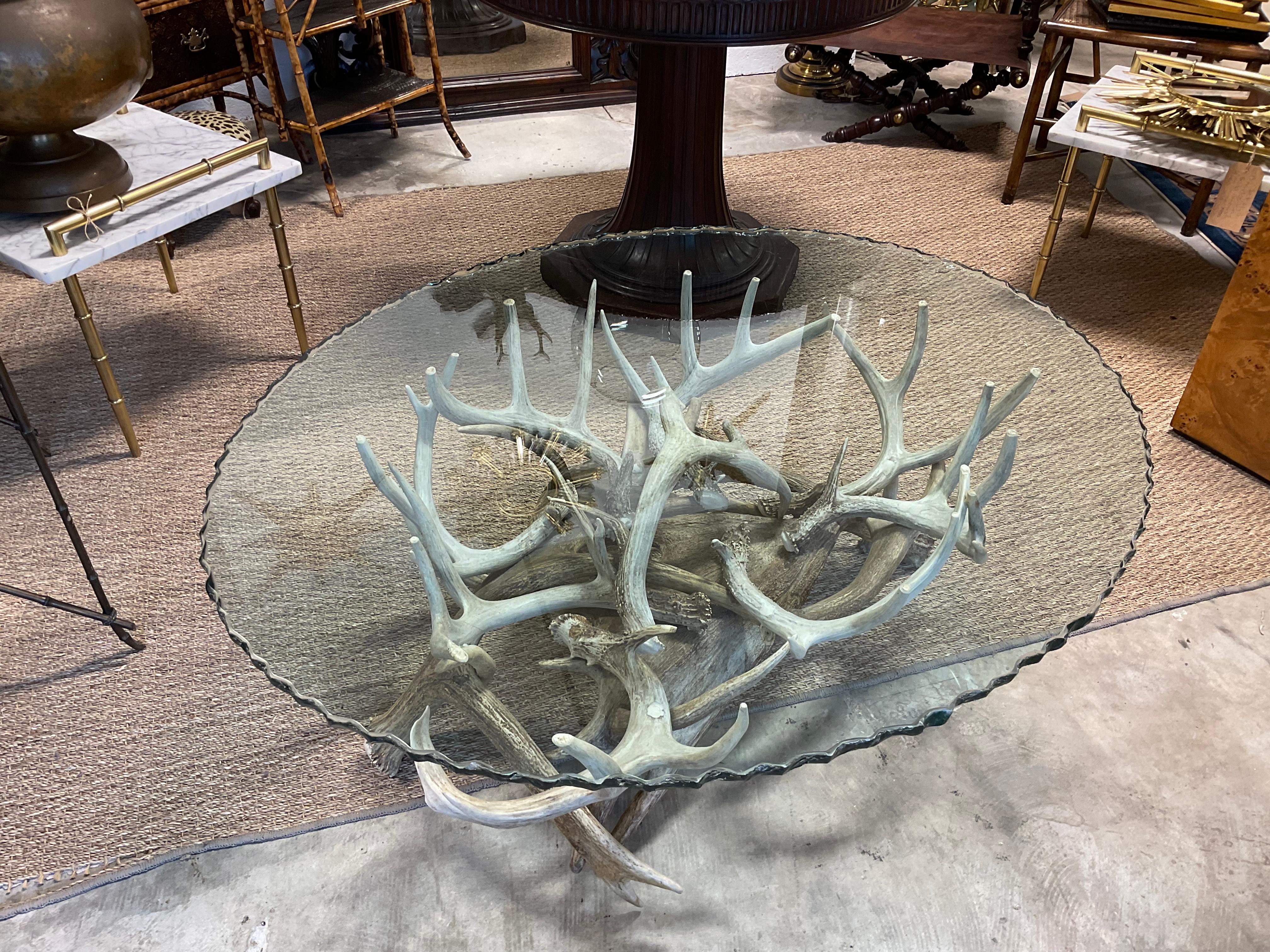Authentic, deer and moose antler table, with scalloped glass top. The pieces have been screwed and epoxied together, so very sturdy, and also an aesthetically pleasing design. .The design is oval with an oval glass scalloped edge top. The base is
