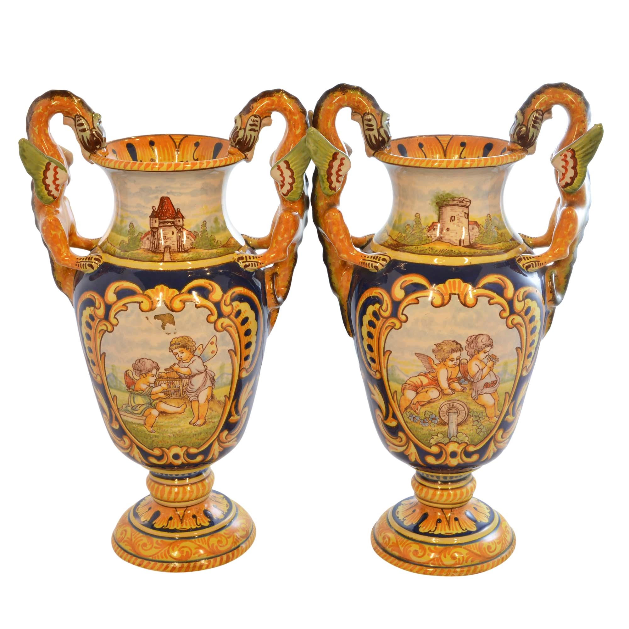 Faience vases feature Rouen hand painted decoration throughout and are from Nevers in Northern France. Both vases feature cherubs in the hand painted body scene and castles on the necks. One features cherubs enjoying the garden; the other has