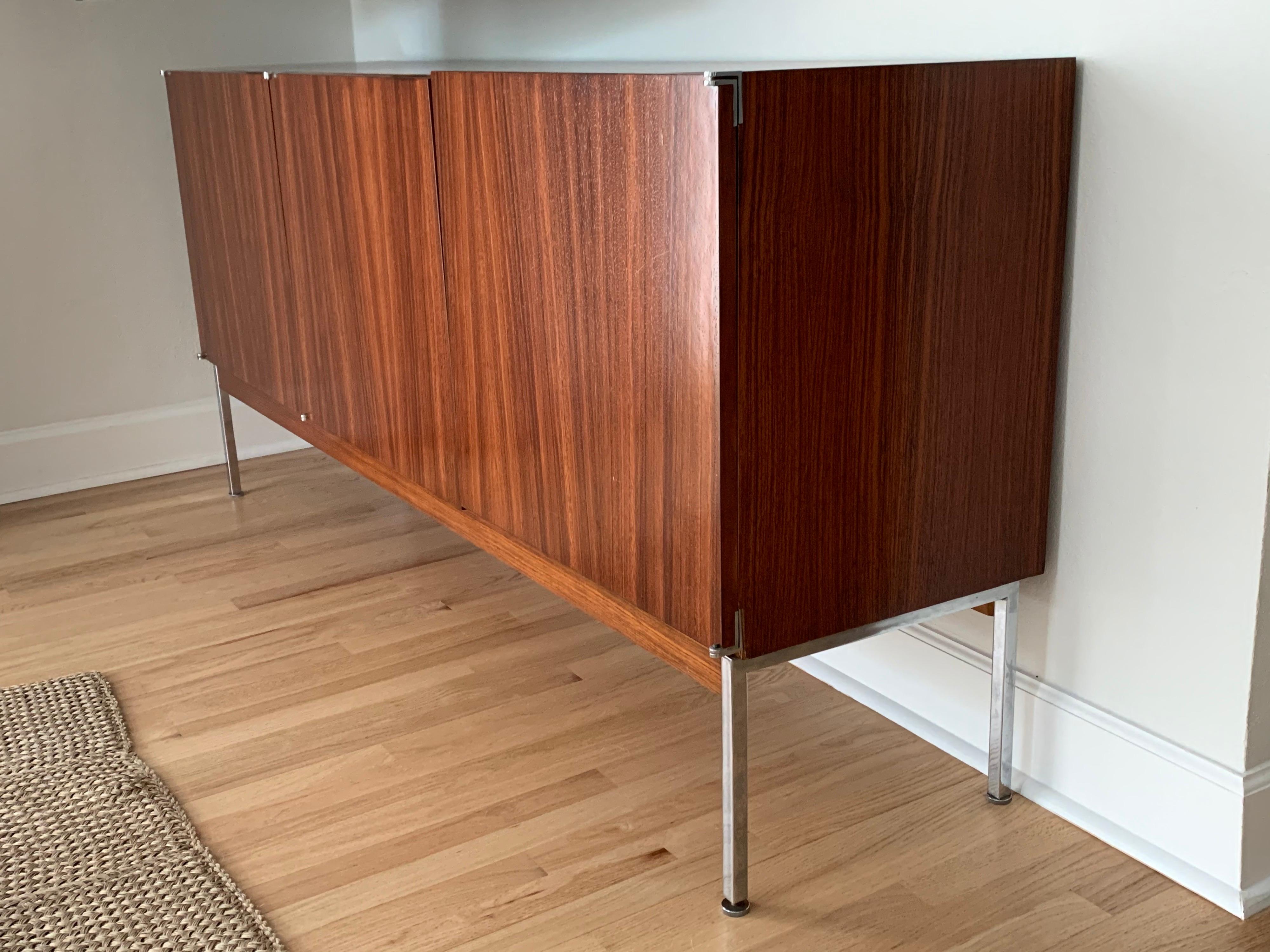 Stunning credenza, sideboard, cabinet, rendered in exquisite rosewood on the exterior case and contrasting light wood interior with 3 doors, 2 of which open to a compartment with a shelf, the left door opens to find 4 gray felt lined drawers. This